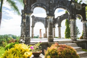 Girl in a flowing dress and hat on a platform with arches in Taman Ujung Water Palace, one of the top things to do in Bali.