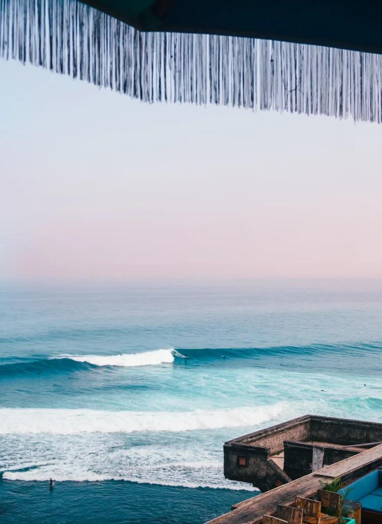 Looking out on a surfer on a wave from the Uluwatu cliff early in the morning, one of the best places to stay in Bali.