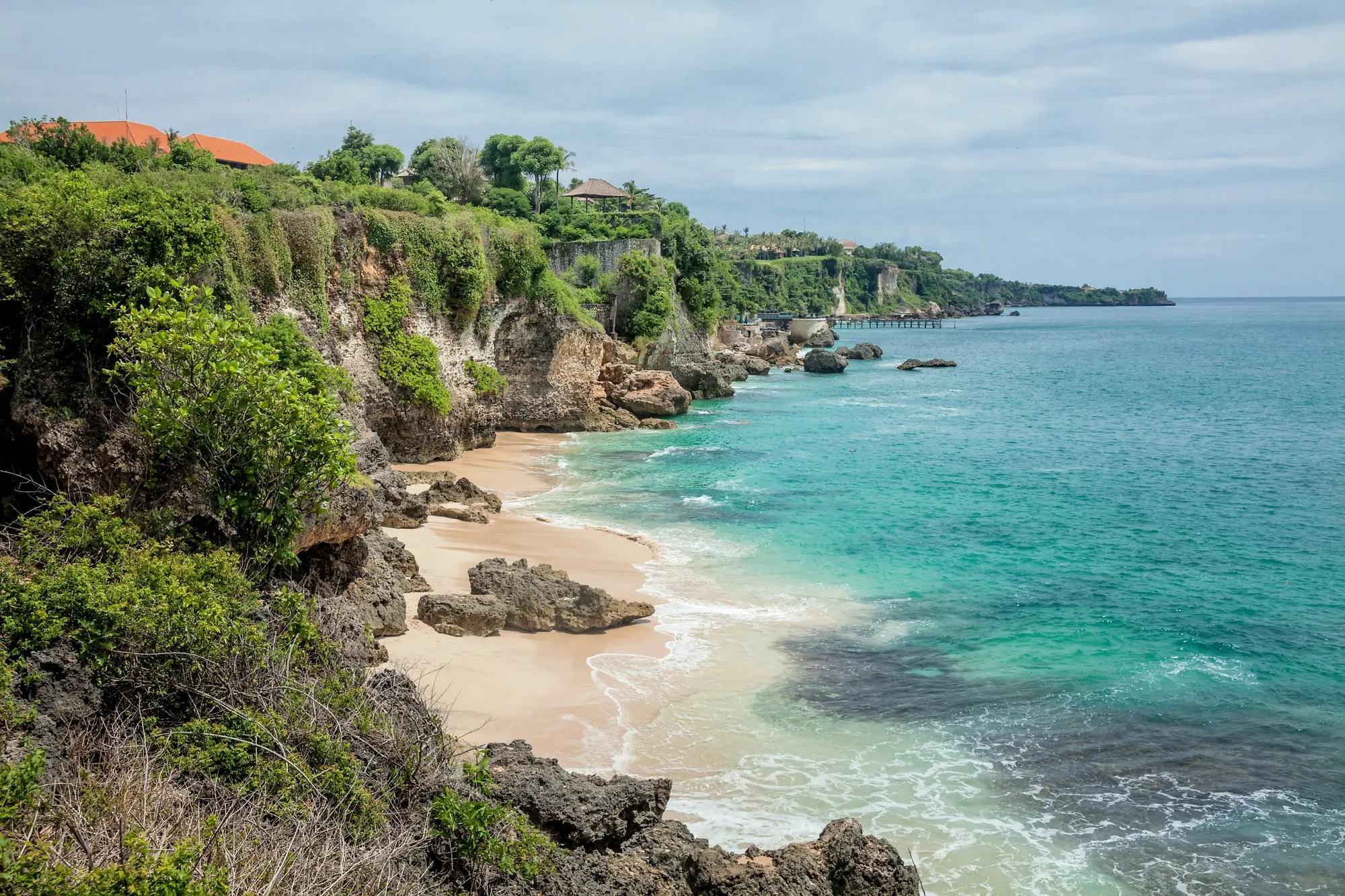 Tegal Wangi, a narrow stretch of sand along limestone cliffs covered in greenery, one of the best beaches in Uluwatu, Bali.