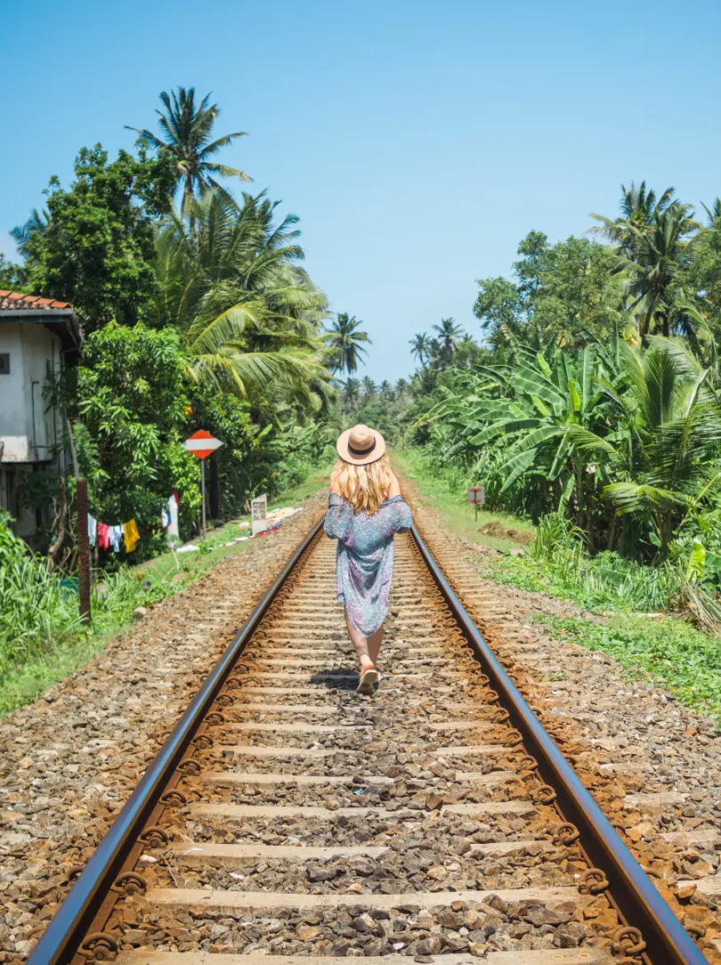 Girl wearing a blue kimono walking on train tracks in Unawatuna, during a 2-week Sri Lanka itinerary.