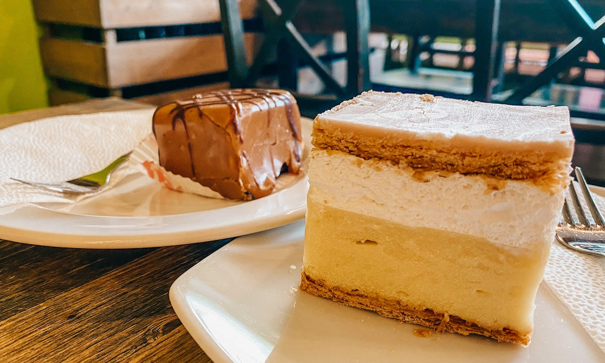 Cremeschnitte, layered yellow and white creme cake on a white plate, best street food in Budapest.