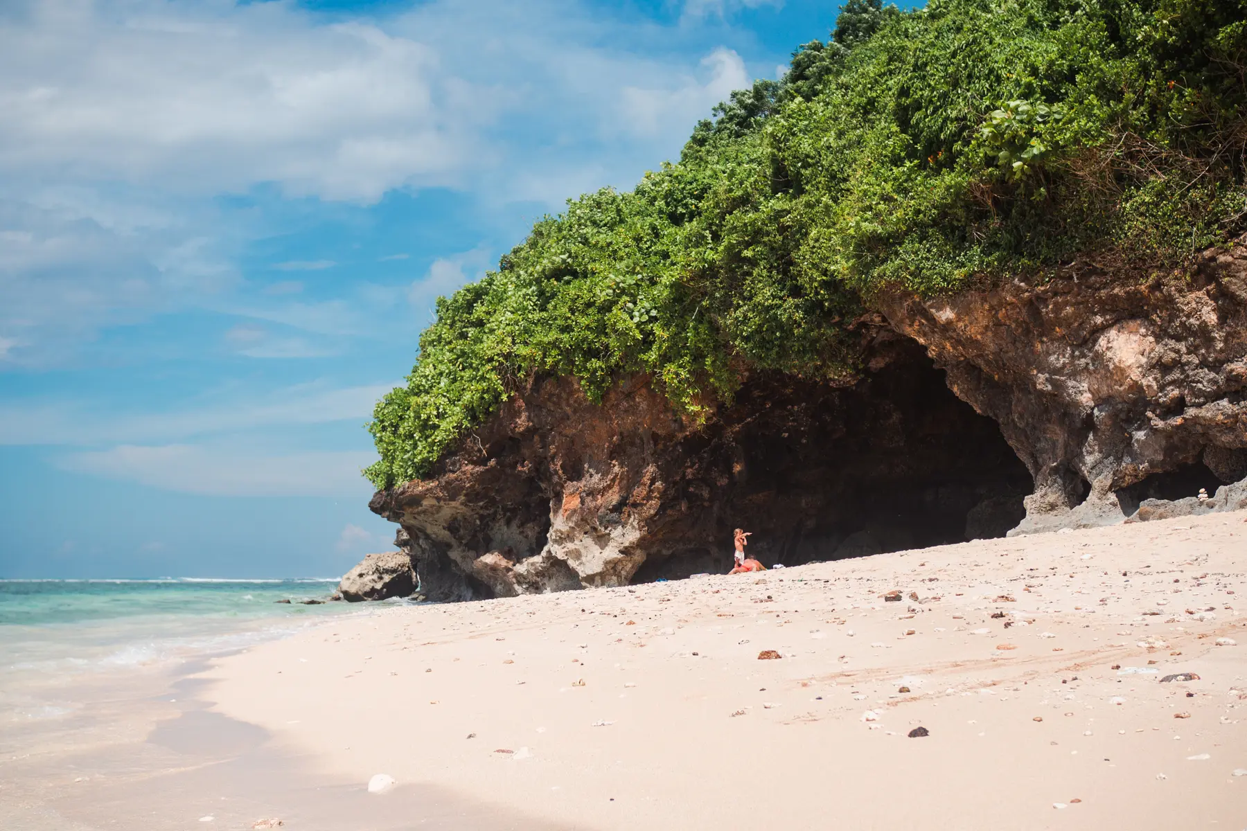 A cave in the limestone cliff covered in greenery on the small Green Bowl Beach in Bali.