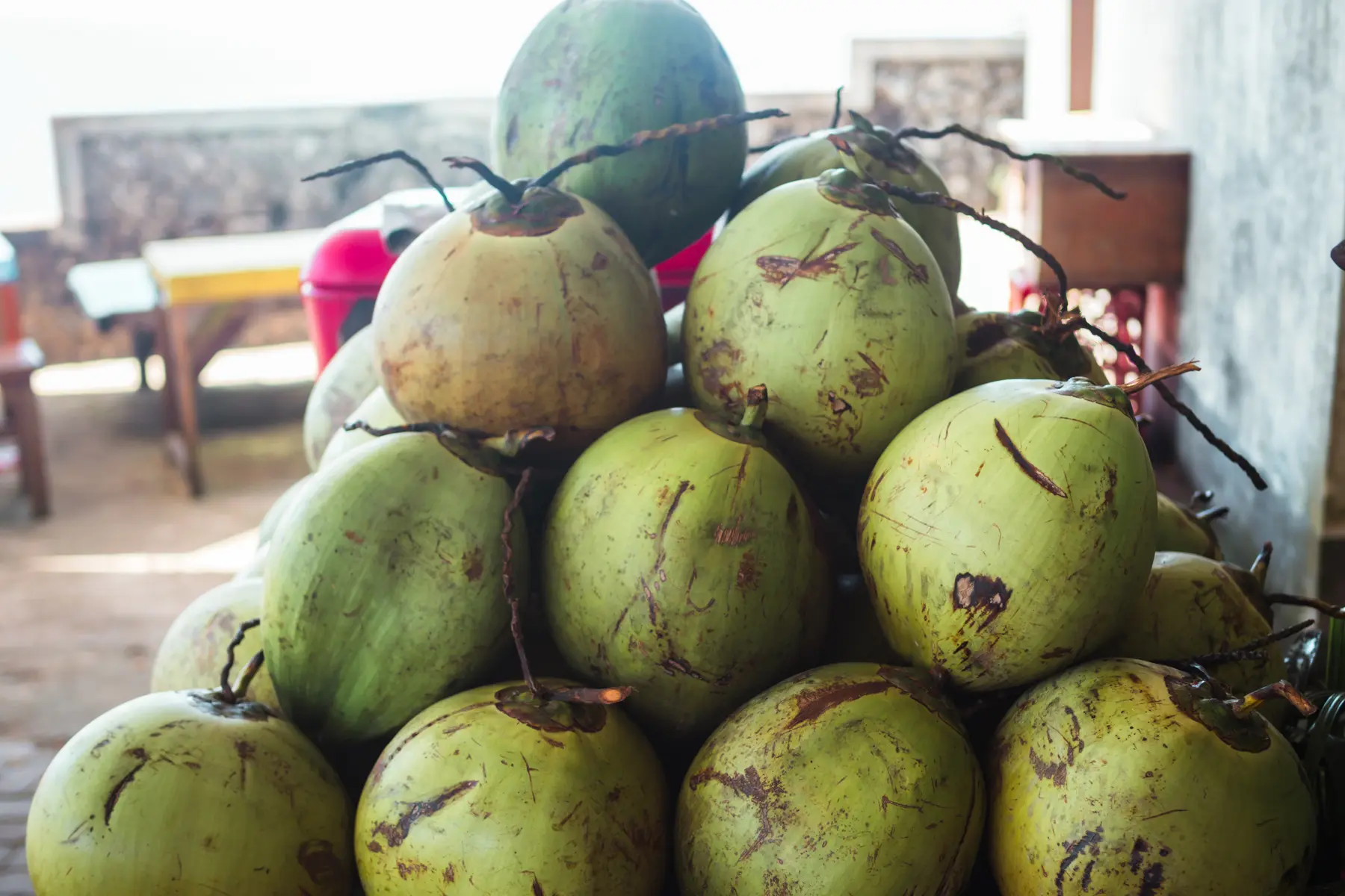 10 green coconuts on a table at a warung close to Green Bowl Beach in Bali.