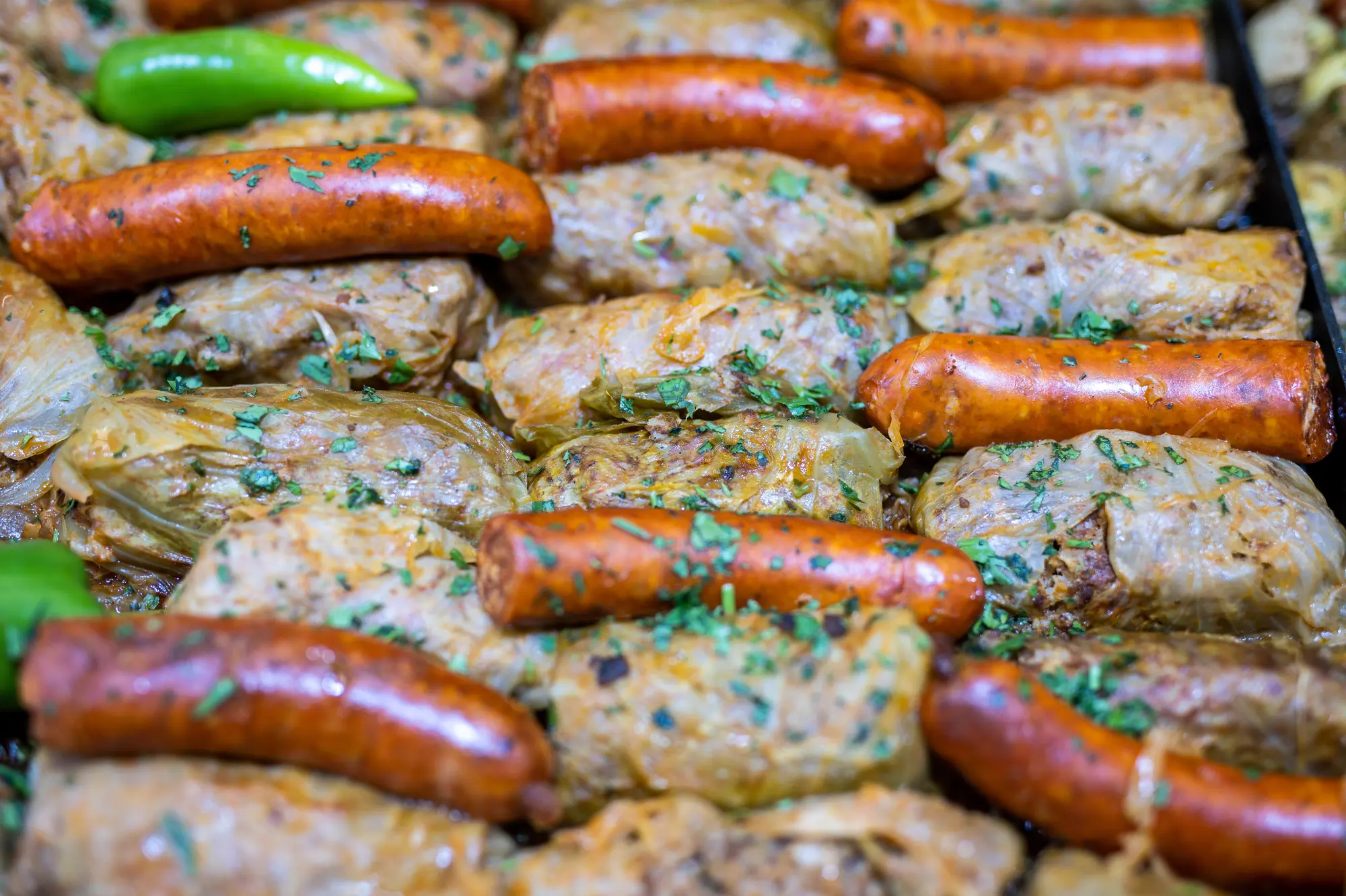 Tray of sausages and stuffed cabbage rolls at a street food stall in Budapest.