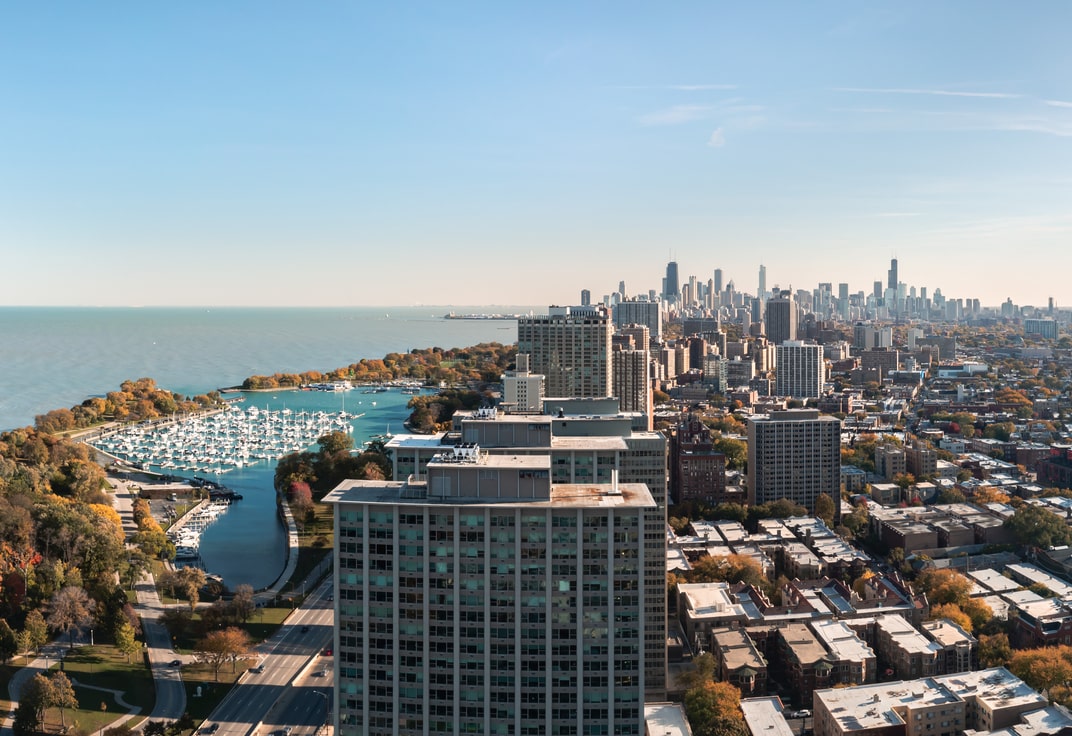 Aerial view of Lakeview and Belmont Harbor with the skyscrapers of Downtown in the background on a sunny day, one of the best areas to stay in Chicago.