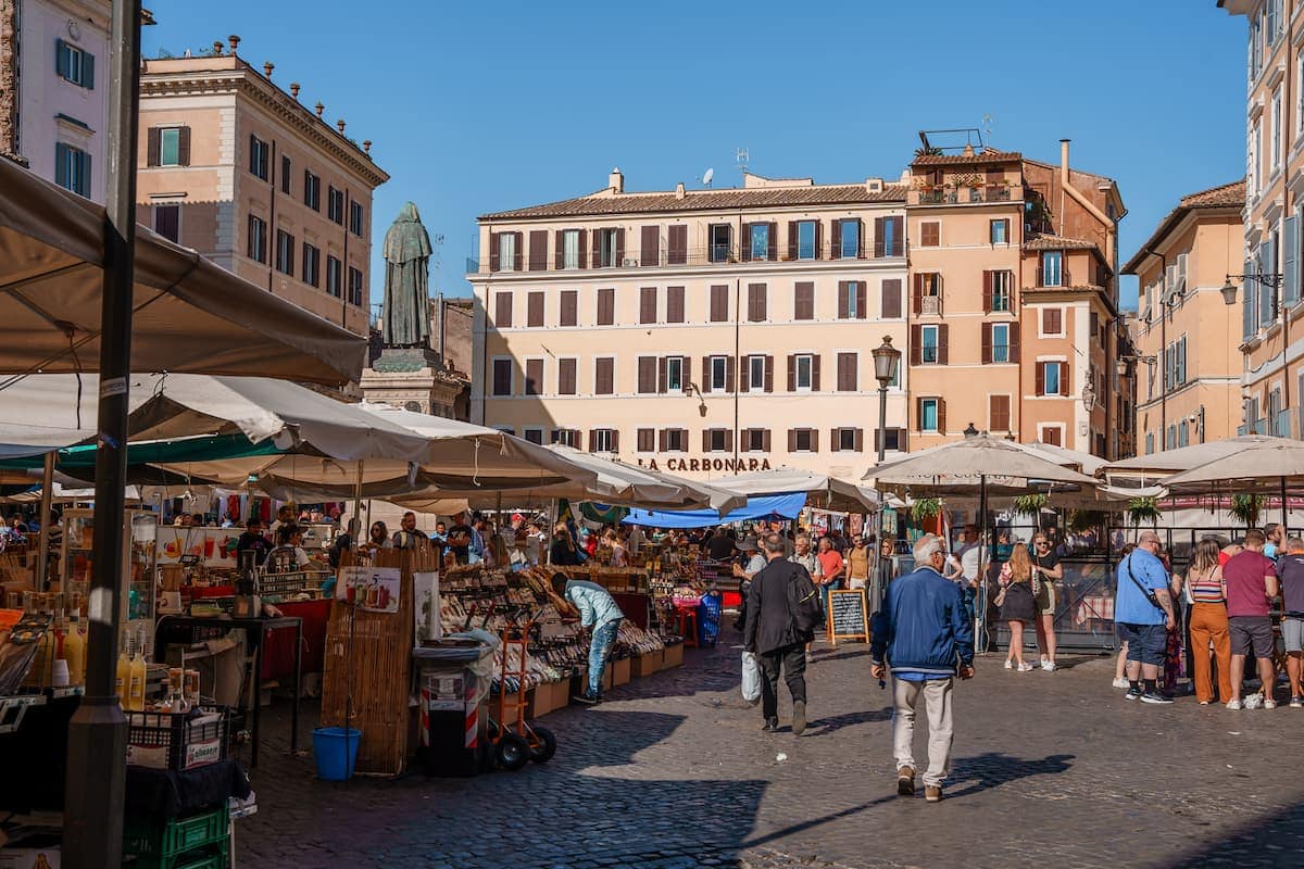People checking out market stalls covered by umbrellas as Campo de' Fiori, is Rome safe to visit?