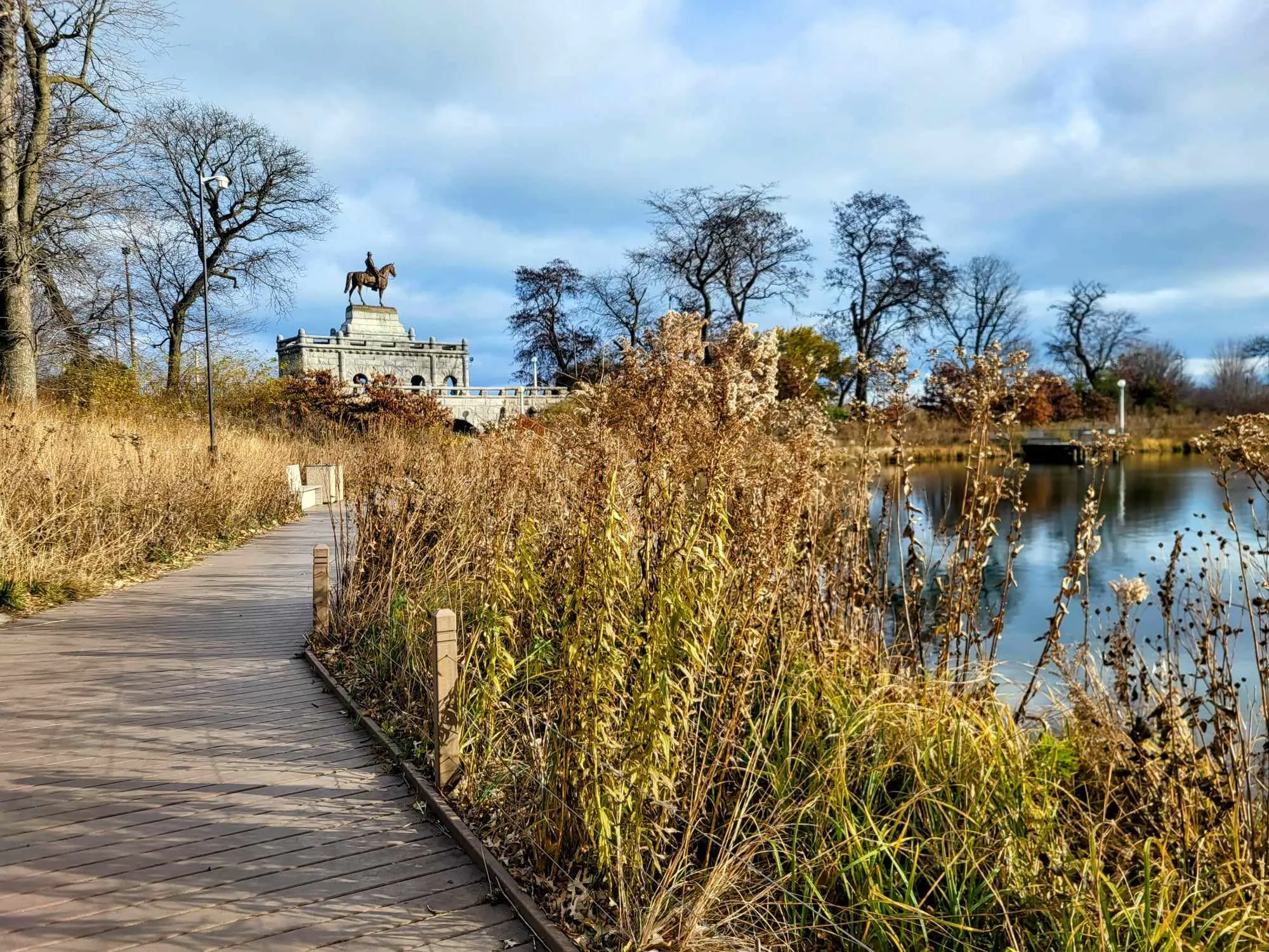 Wooden walking path leading towards a statue of a man on a horse in Lincoln Park, one og the best areas to stay in Chicago.