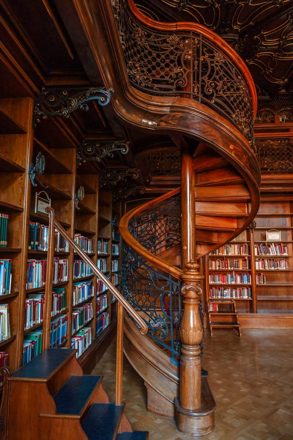 Intricate wooden spiral staircase inside the Ervin Szabo Library, a hidden gem in Budapest.