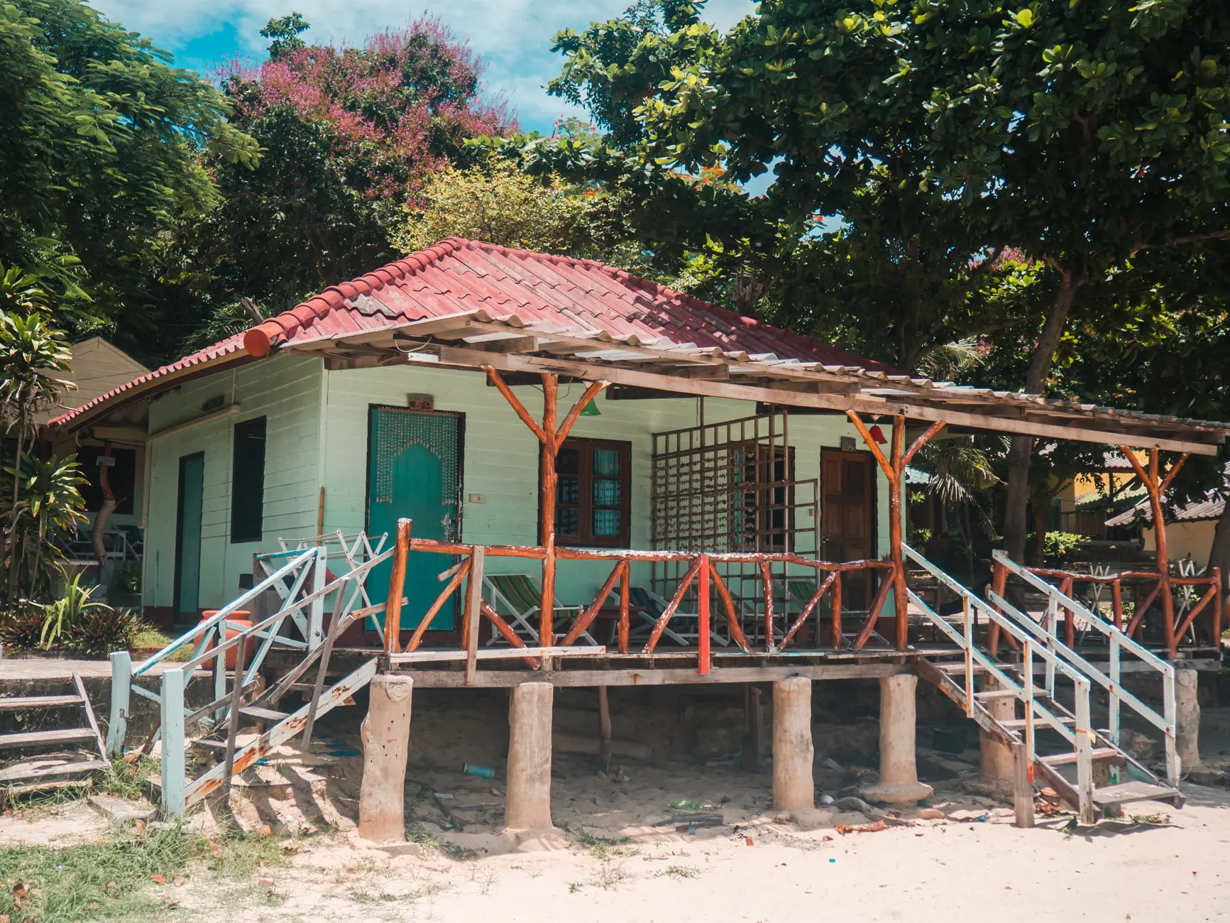 Boho rustic raised turquoise beach bungalow decorated with seas shells and surrounded by greenery on Koh Samet in Thailand vs. Indonesia