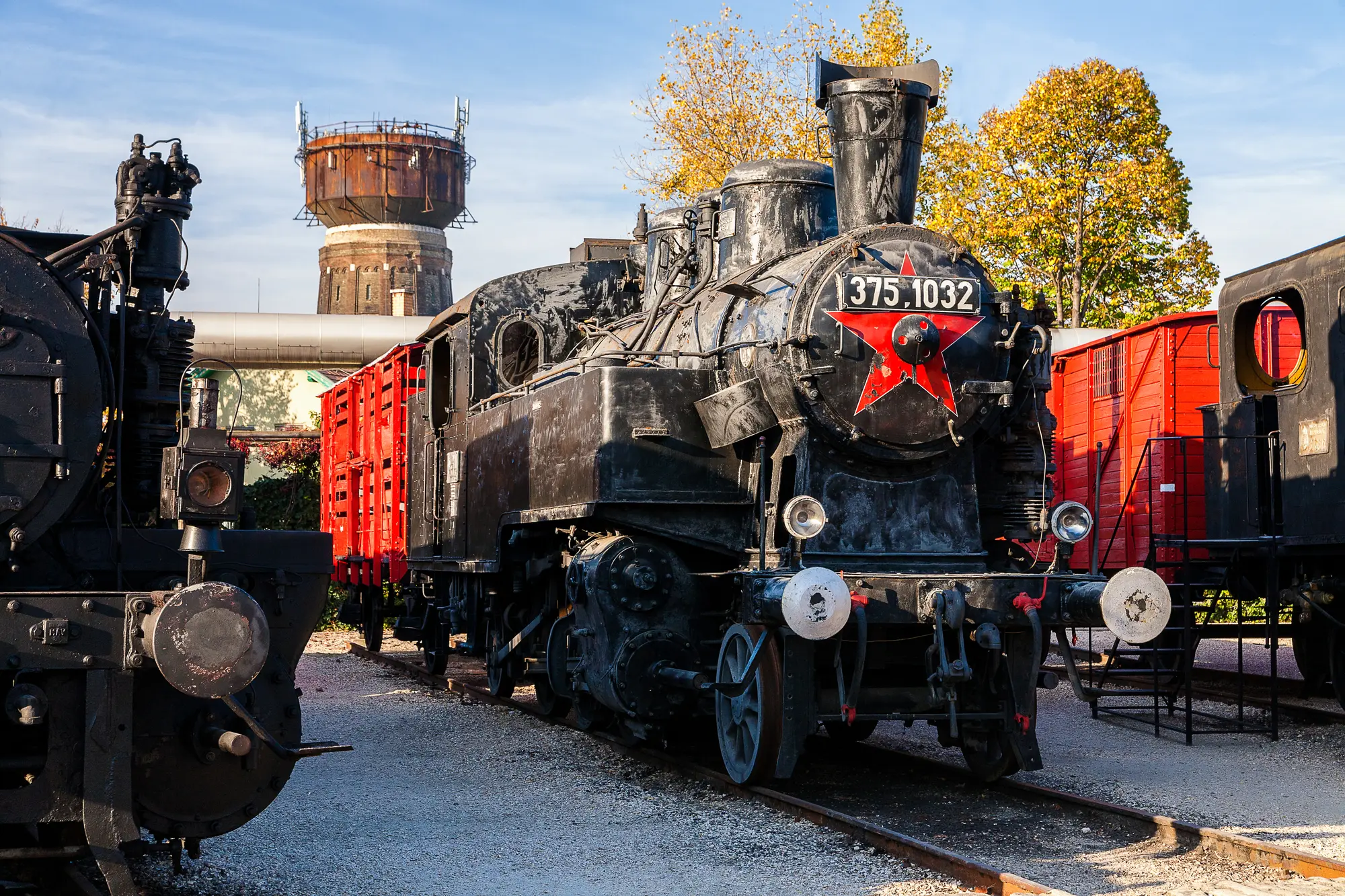 Old black steam locomotive with red carts and a red star in the front at the Hungarian Railway Museum, a hidden gems in Budapest. 