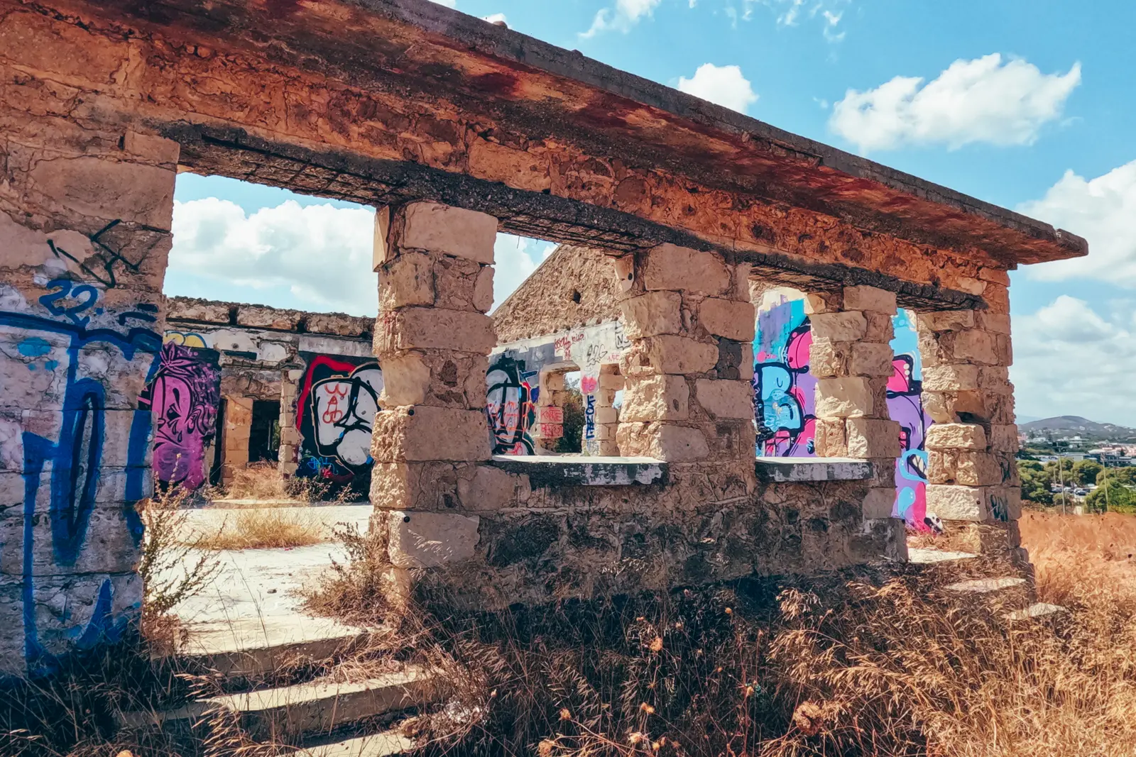 Old ruin building with colorful tagging on the hill overlooking Agii Apostoli Beach in Chania.