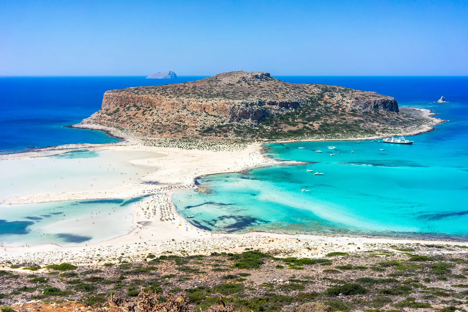 View from the top of a hill overlooking Balos Lagoon with white sand and shallow turquoise water running out to Gramvousa Island, most beautiful beach in Chania.