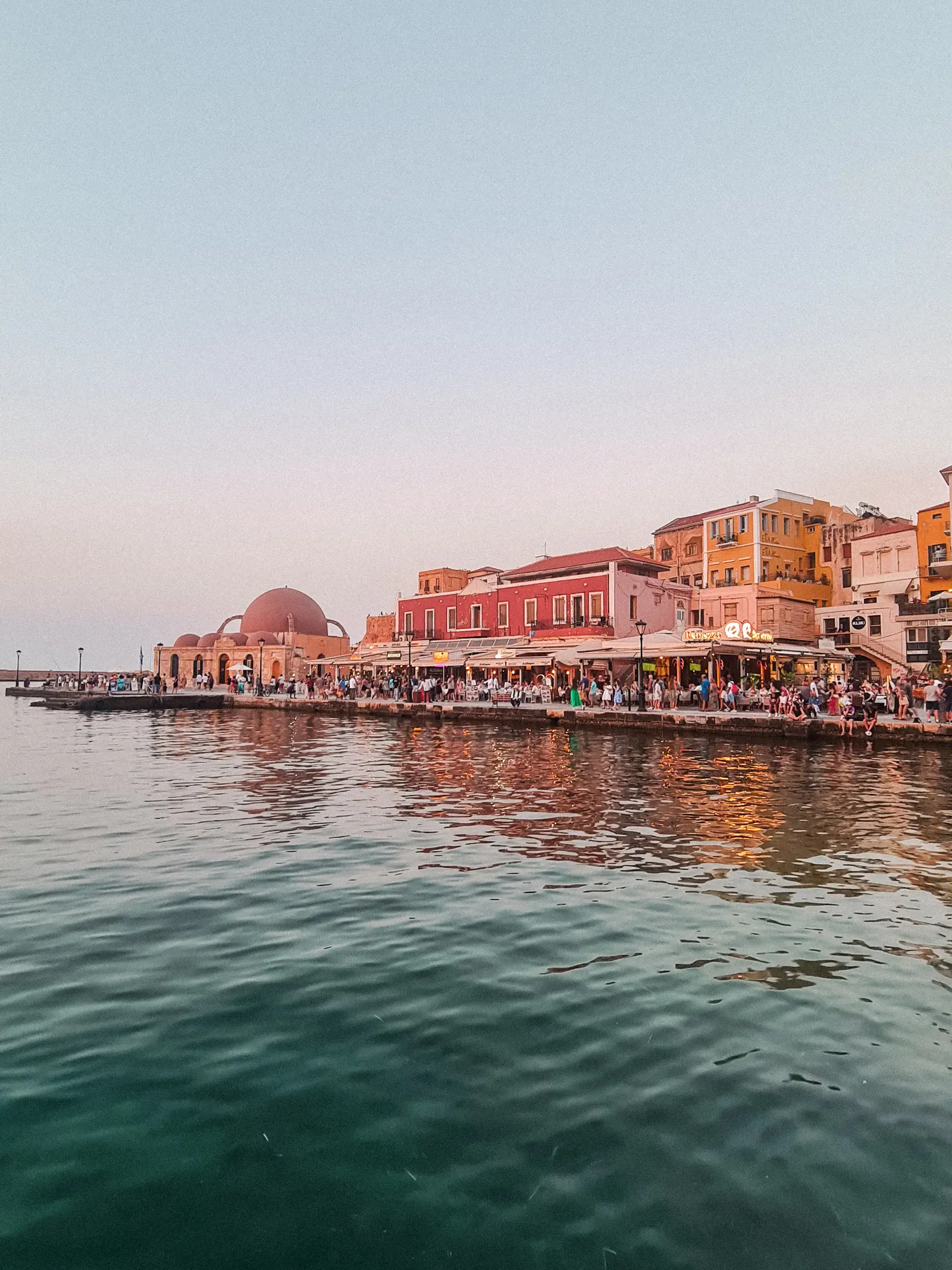 Yellow and red buildings along the Venetian Harbor in Chania Old Town at dusk.