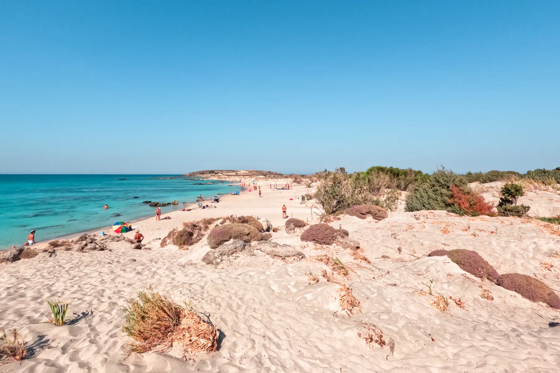 View of turquoise water, light beige sand dunes and the beach at Elafonisi Island in Crete on a sunny day.