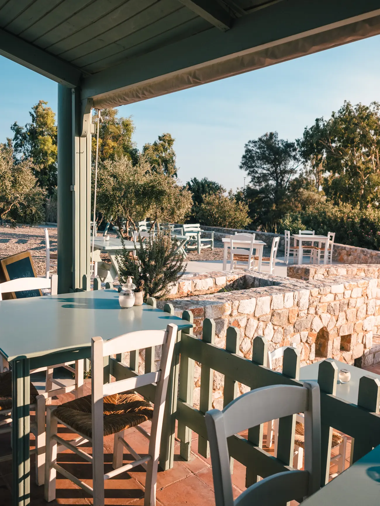 View of olive green tables and chairs and a stone patio at Elafonisi Resort by Kalomirakis Family Restaurant in Crete.