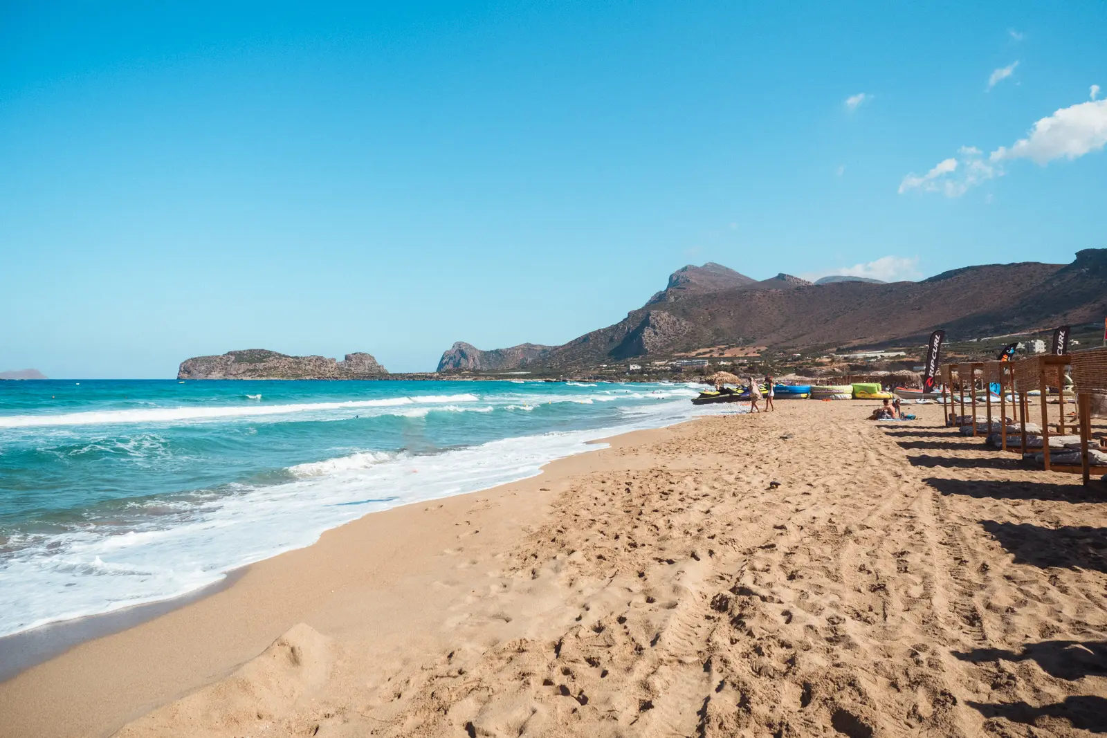 Golden sand and turquoise water with mountains in the background at Falasarna Beach in Crete.