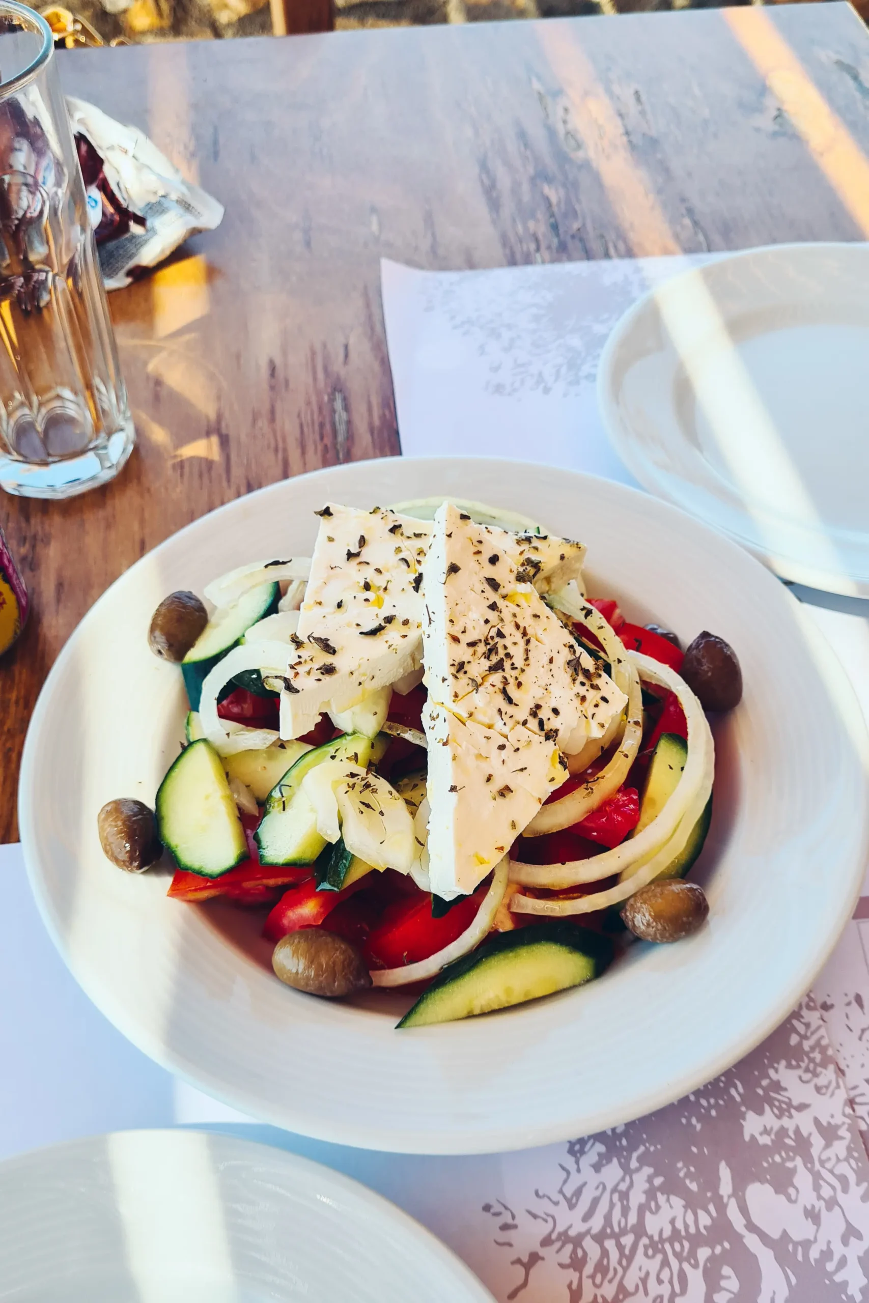 Greek salad on a white plate, during a stop on the coastal route from Falasarna to Elafonisi Beach.