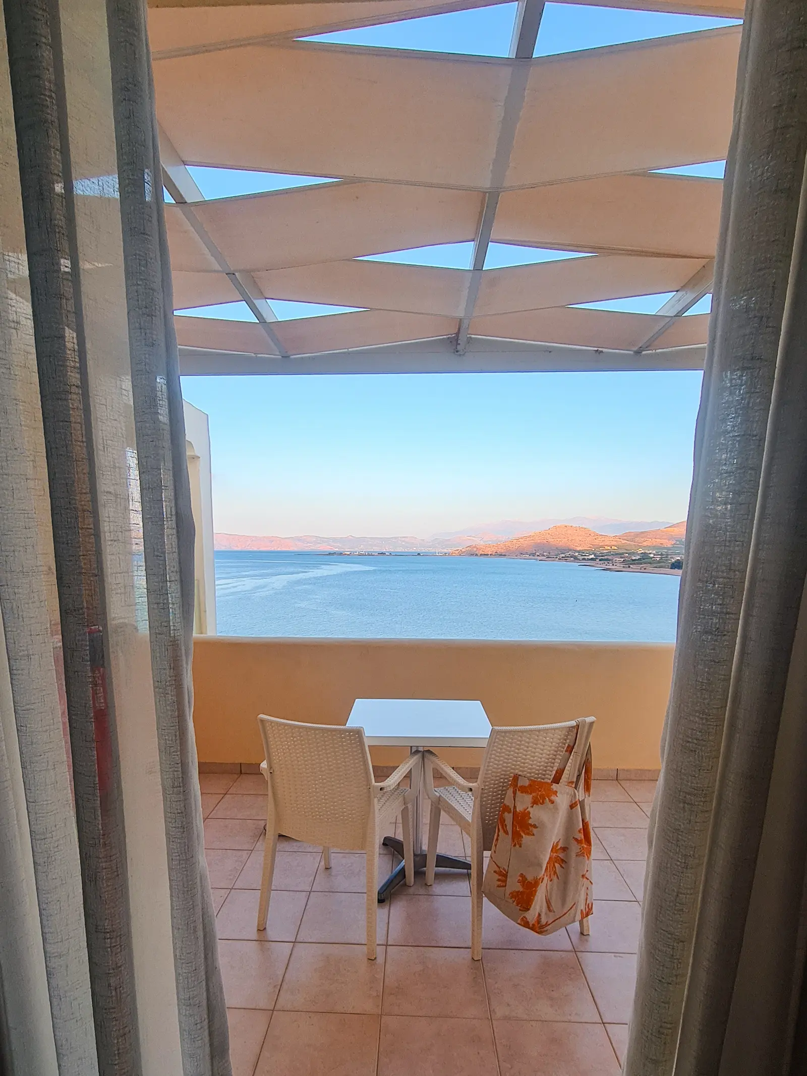 White table and two chairs on a veranda overlooking a pastel colored sunset above the ocean close to Balos and Falassarna Beach in Crete.