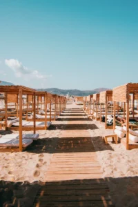 Wooden pathway between cabanas with white mattresses on Falassarna Beach in Crete.
