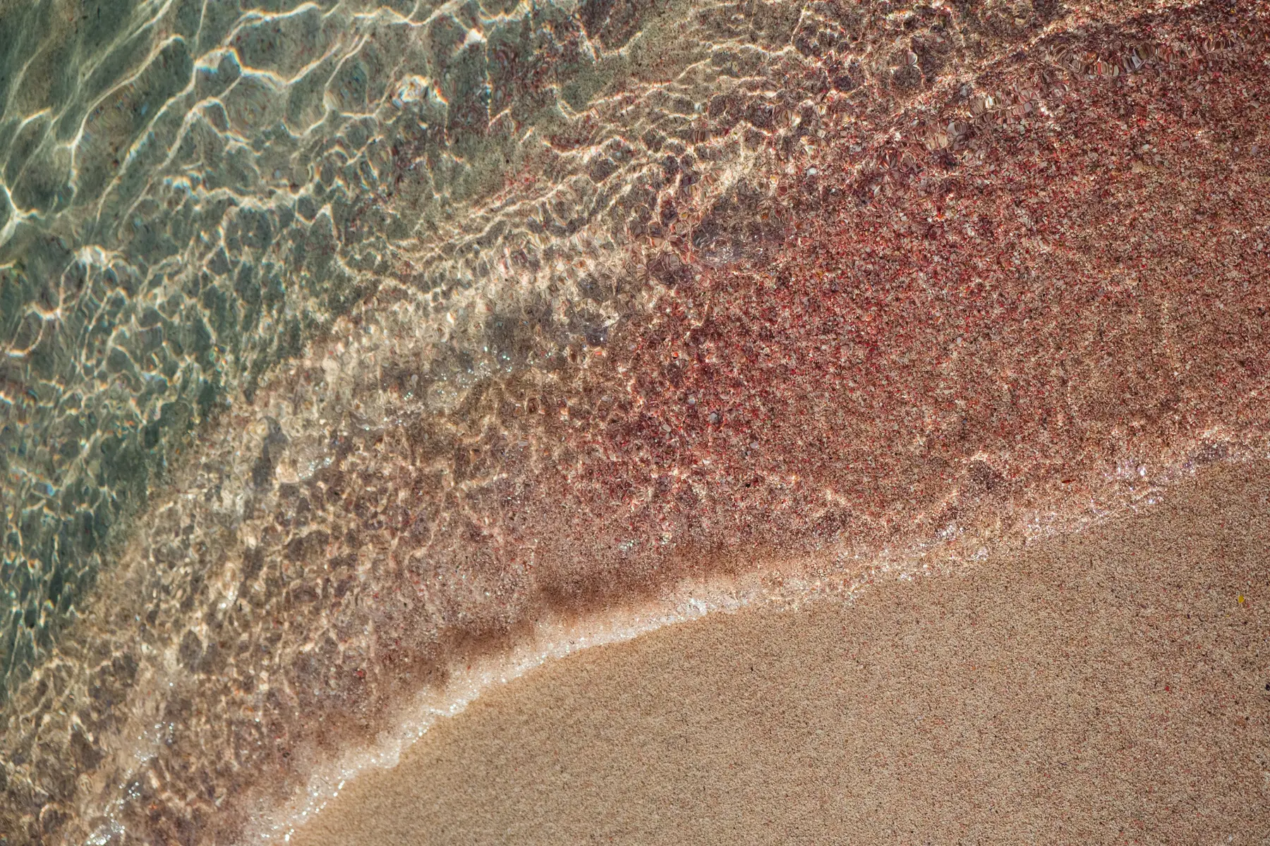 Close up of pink sand and turquoise shallow water at Elafonisi Beach in Crete.