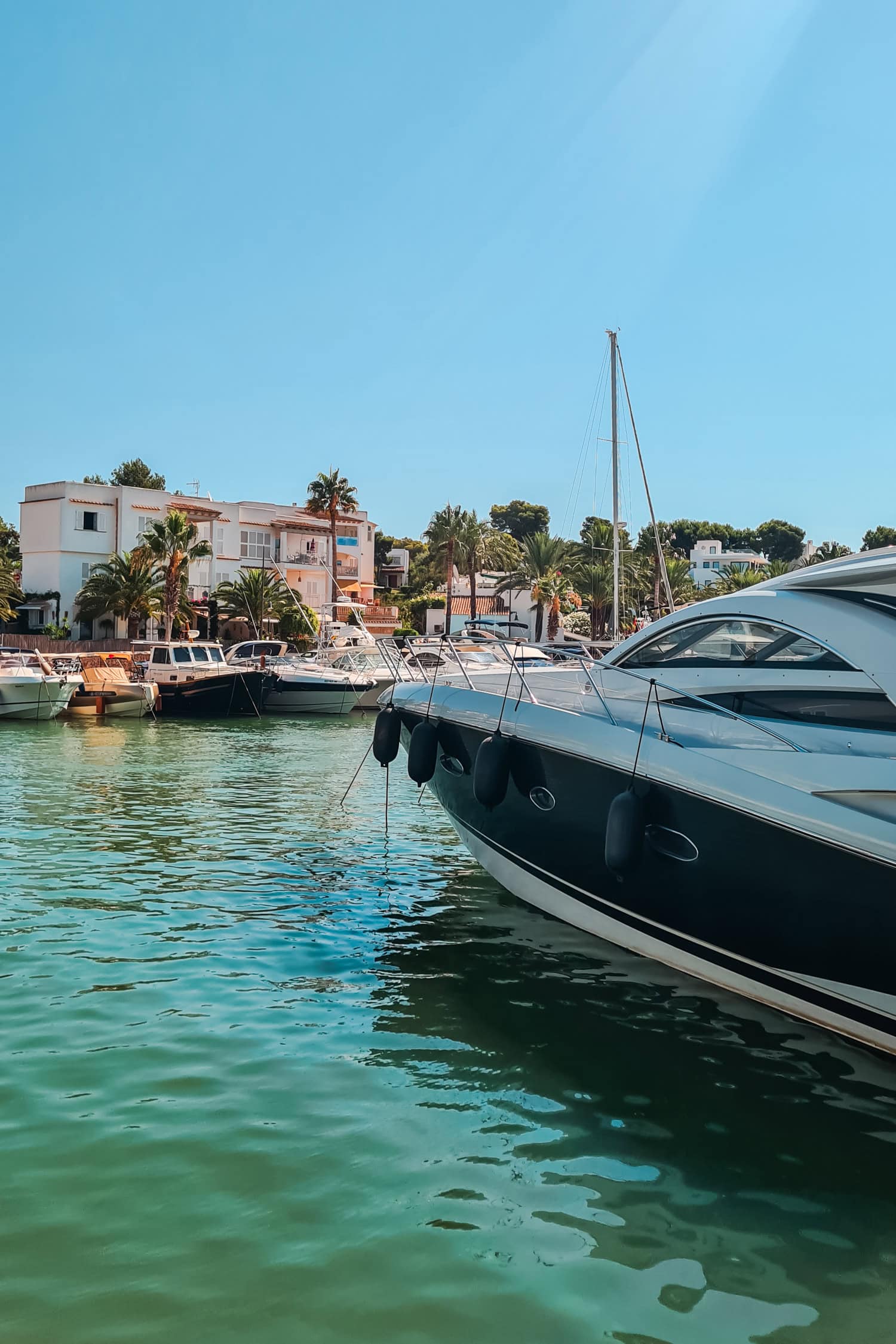 Canal with turquoise water and boats and yachts on both sides in Cala d'Or Mallorca.