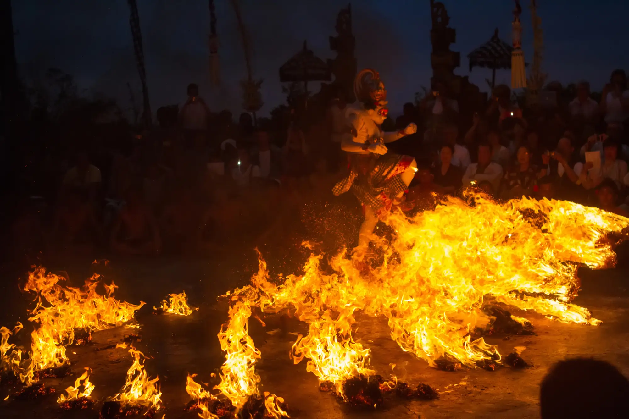 Traditional Balinese Kecak Fire Dancer standing in a ring of fire at Uluwatu Temple in Bali.