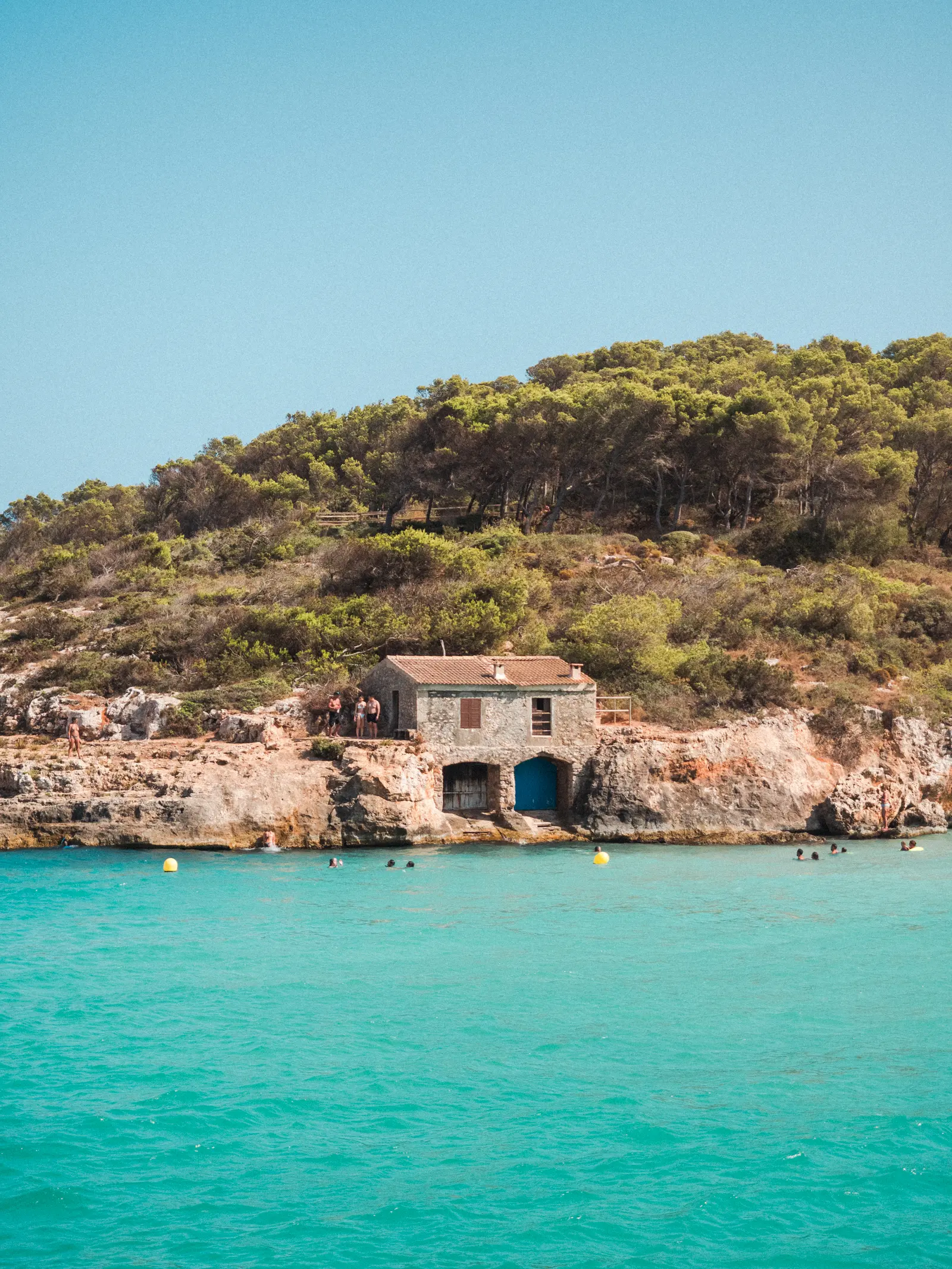 Mallorca - Old stone fisherman's house with dark blue doors down by the turquoise ocean at Cala S'Amarador, one of my favorite beaches in Mallorca