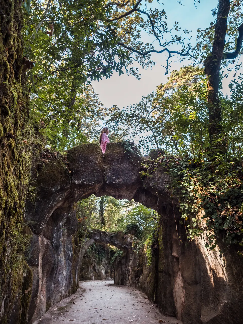 Road under two simple stone bridges in the forest of Quinta da Regaleira in Sintra Portugal.