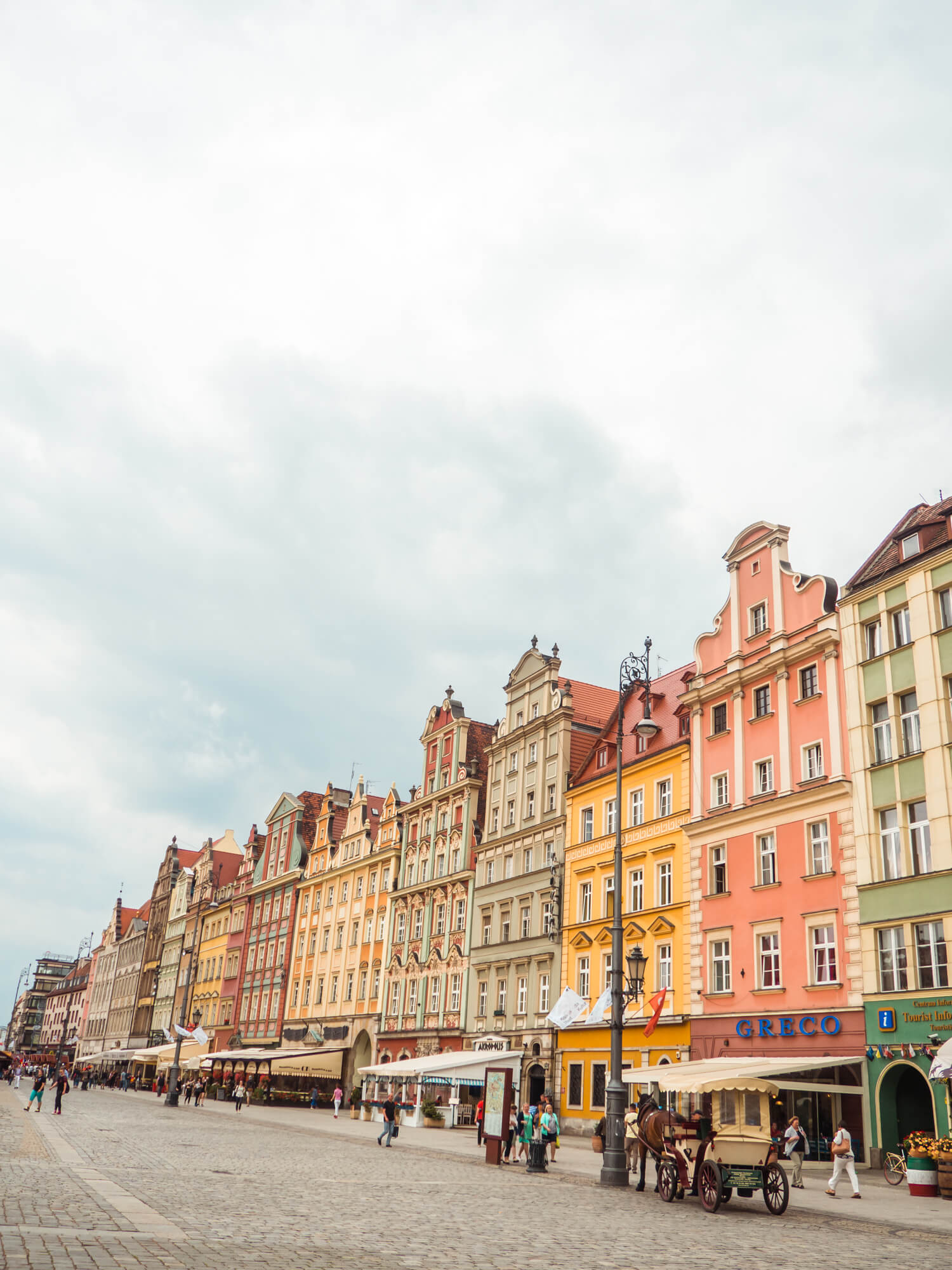 Row of green, yellow and pink houses in Wroclaw Old Town on a gloomy day.