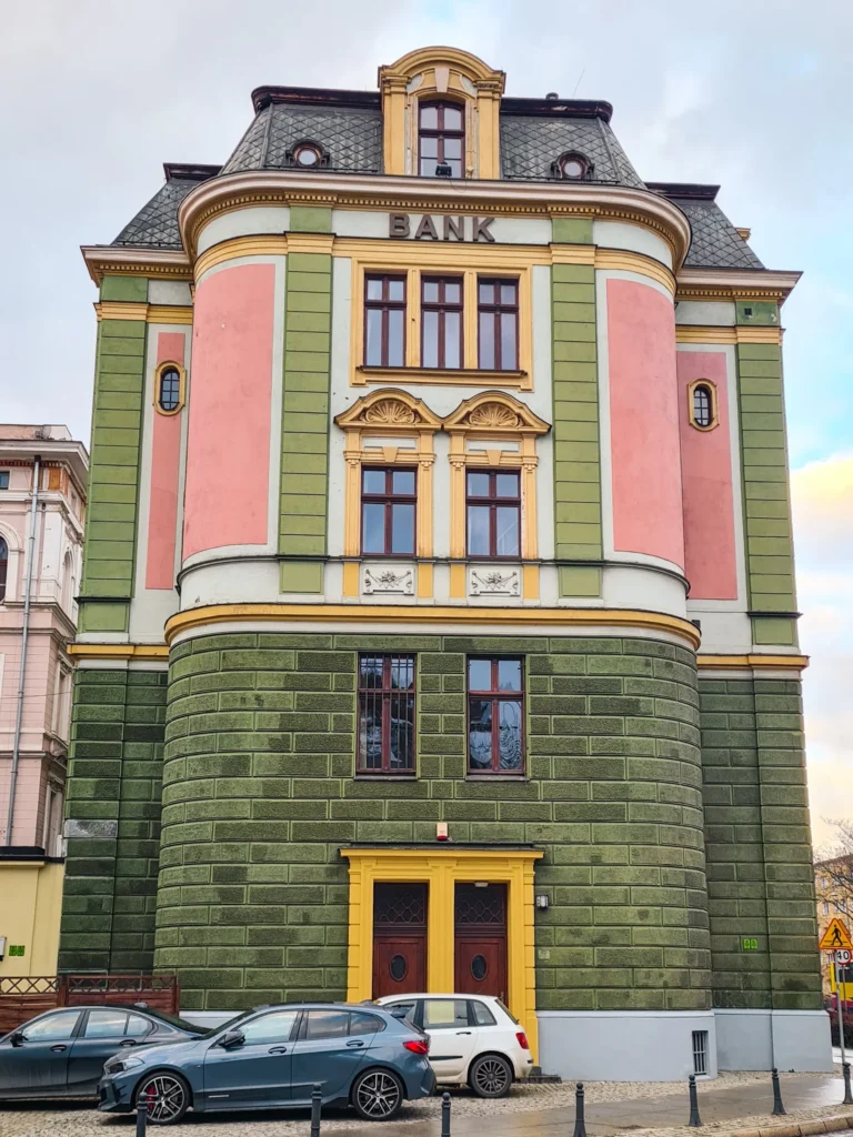 Art Deco style green stone bank building with pink and yellow details, another one of the most spectacular architecture examples in Wroclaw.