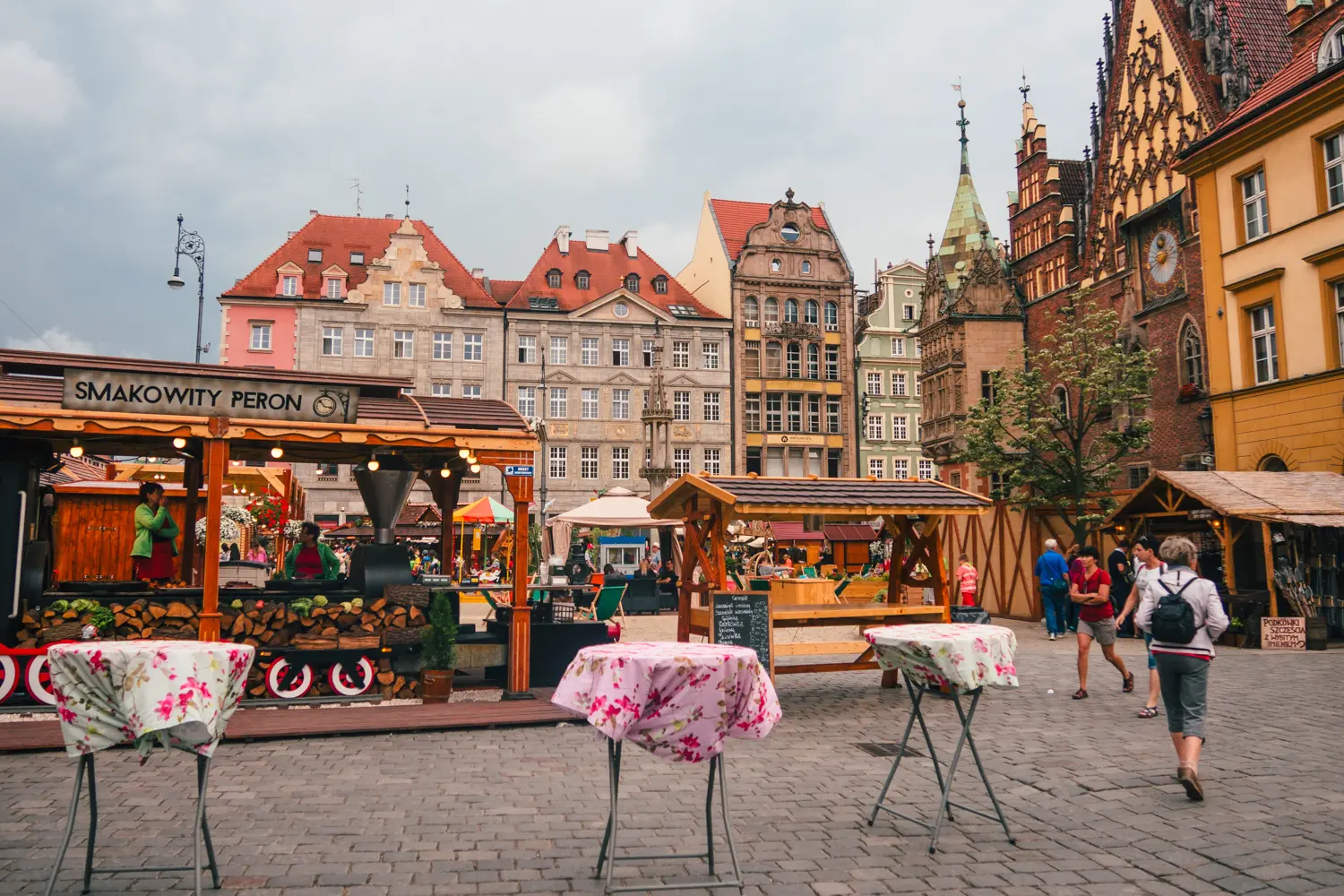 Two market stalls selling food surrounded by colorful buildings on Wroclaw Old Town Market Square.