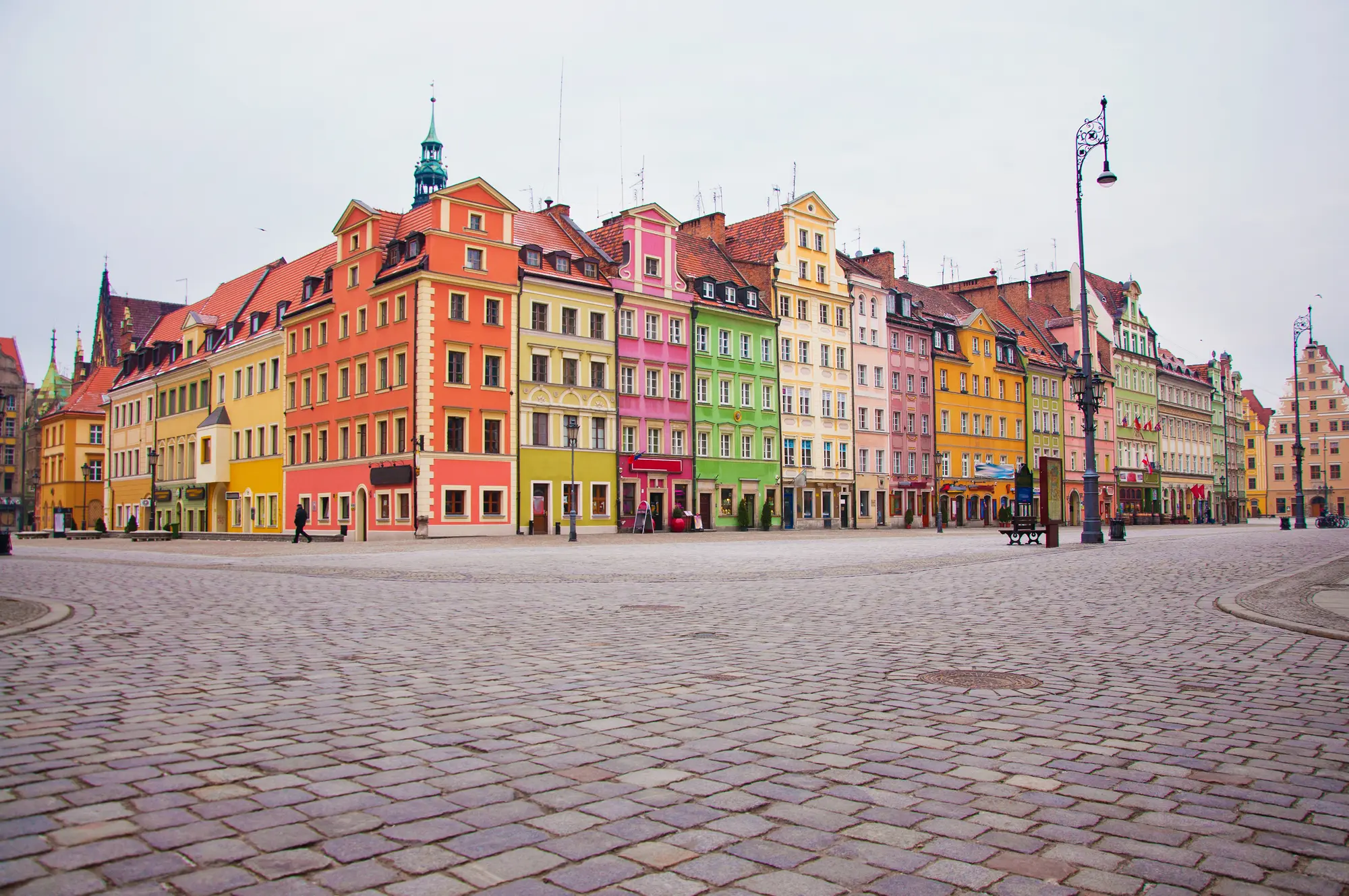 Row of colorful houses, orange, pink, green and yellow, along the cobbled old town market square in Wroclaw.