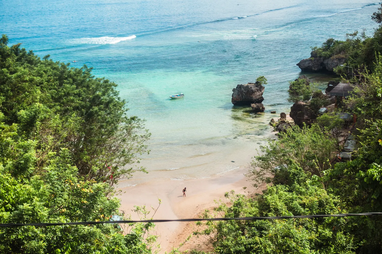 A person walking across the sand at Padang Padang beach in Bali seen from above. Bali or Lombok?