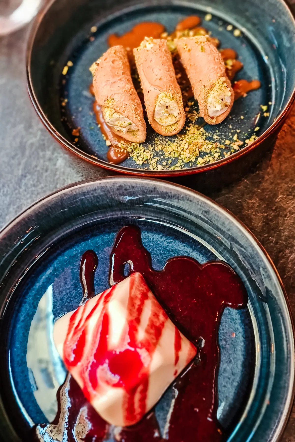 Blue plate with square Panna cotta with strawberry sauce and three small cannolis with caramel sauce at Dolabella Due, one of the best Restaurants in Krakow.