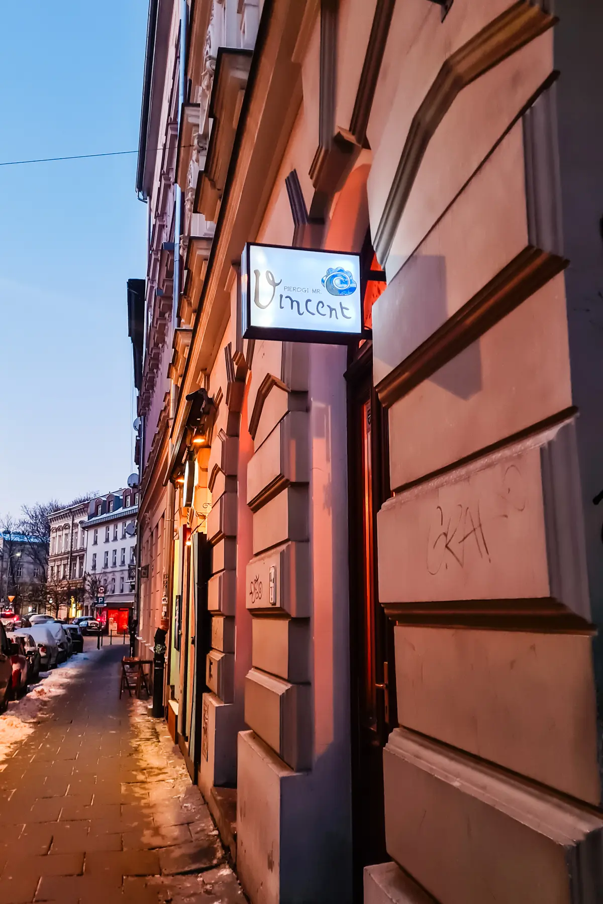 Close of up blue and white Pierogi MR Vincent sign on an old building in Krakow at night, one of the best restaurants in Krakow.
