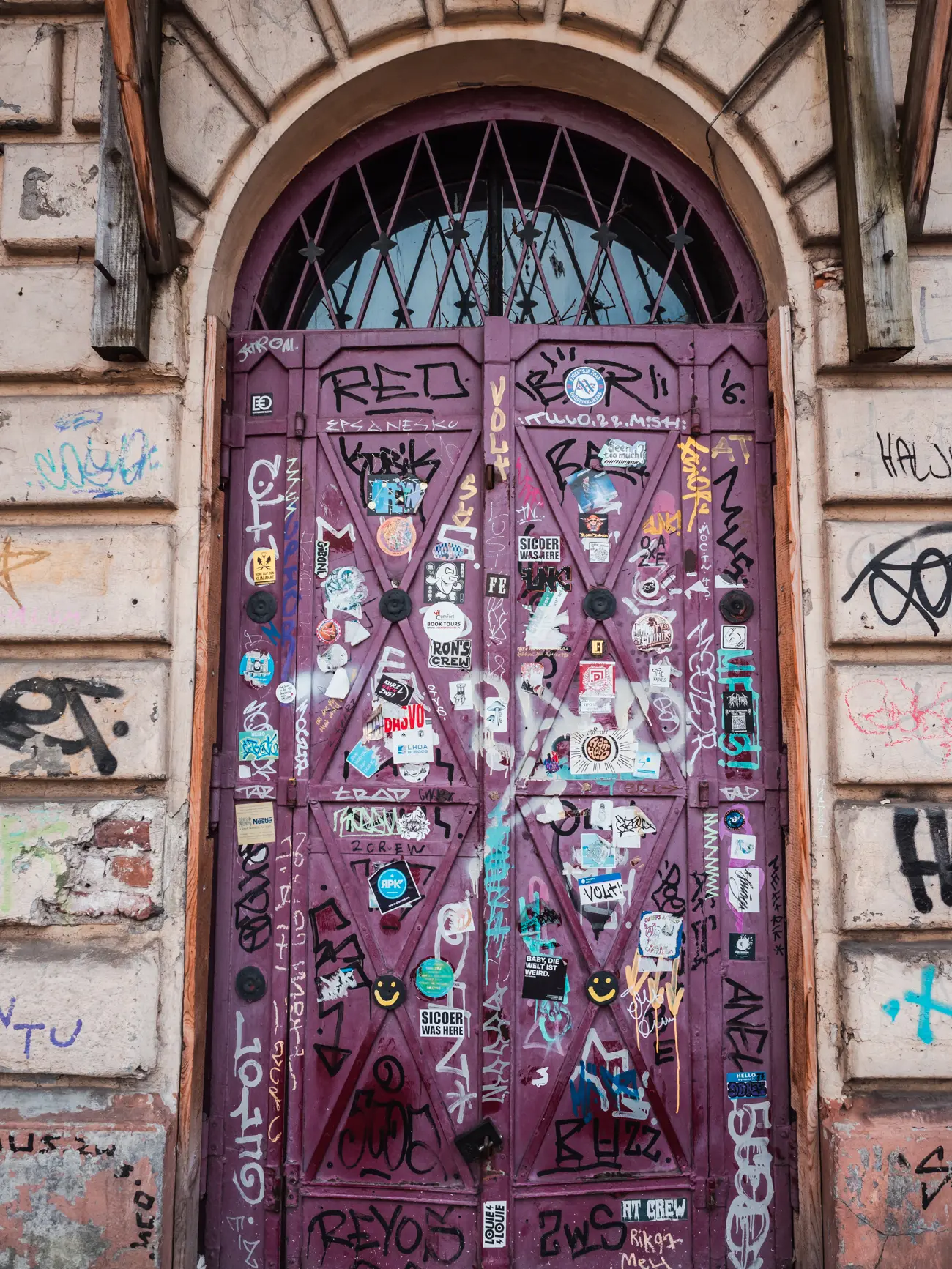 Purple door with a half circle window on top covered in graffiti, one of the top things to see in Kazimierz.