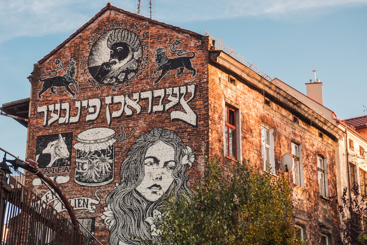 Red brick building in Kazimierz with a black and white Jewish themed mural.