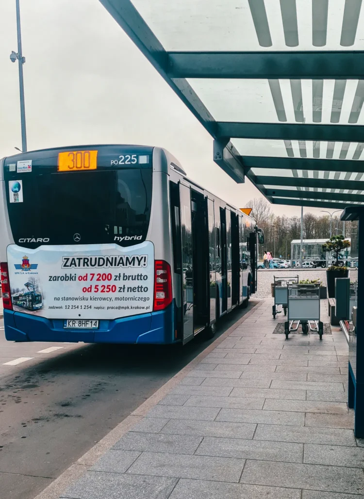 White and blue bus with yellow number 300 waiting at a stop outside Krakow Airport to go to the city center.