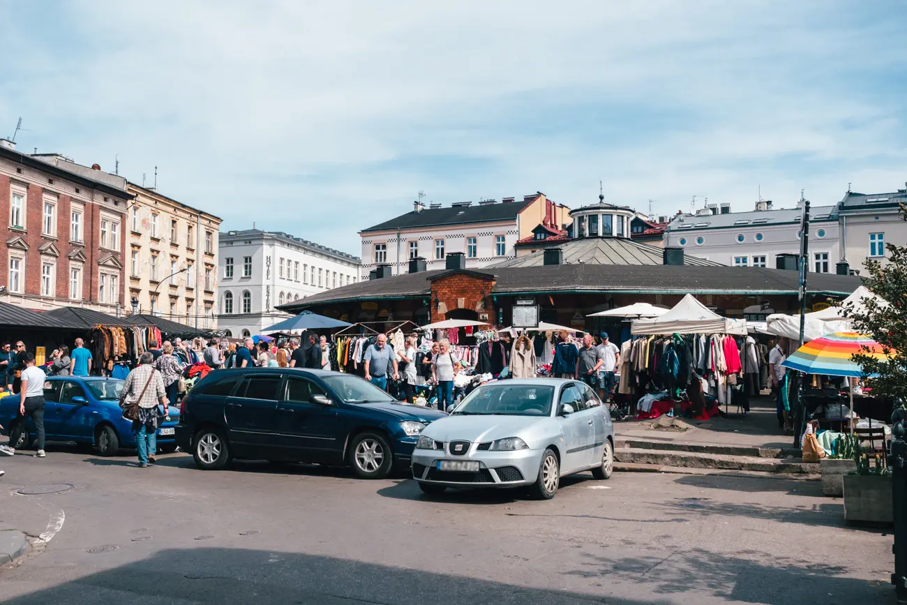 Chaotic market stall with clothes and a blue, black and silver car in front at Plac Nowy square in the heart of Kazimierz, Krakow. 