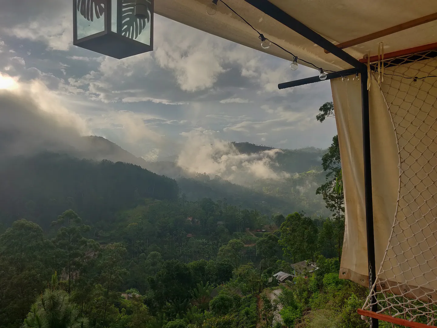 Looking out over the rolling hills of Sri Lanka on a misty morning from a cool Airbnb set on a hillside with nets to lay on. One of the best Airbnbs in Sri Lanka for photography.