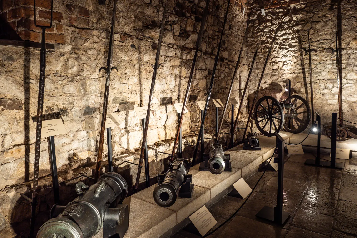 Medieval pikes and canons in the dark stone cellar at Wawel Castle Armoury.