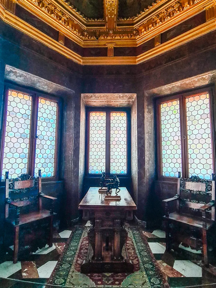 Dark wood room with gold detailed on the ceiling and stained glass windows in the Royal Apartments at Wawel Castle in Krakow.