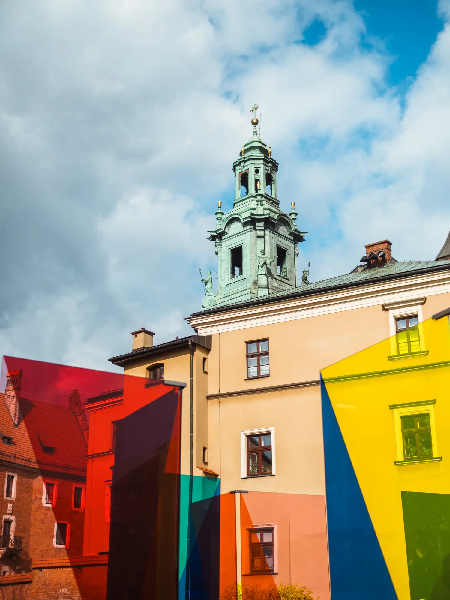 Red, yellow, blue and green glass art installation at Wawel Castle with a metal spire in the background at Wawel Castle in Krakow.