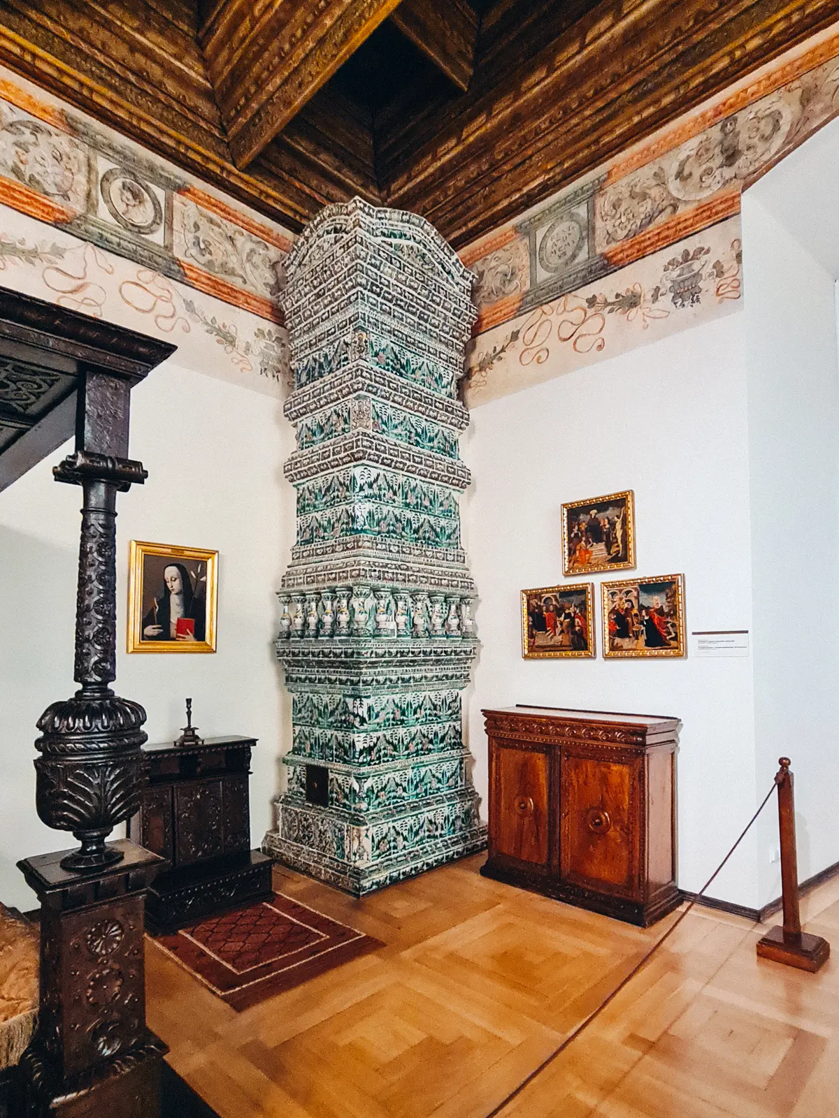 Impressive green and white patterned tiled stove in a white room with detailed roof, in the Royal Apartments at Wawel Castle.