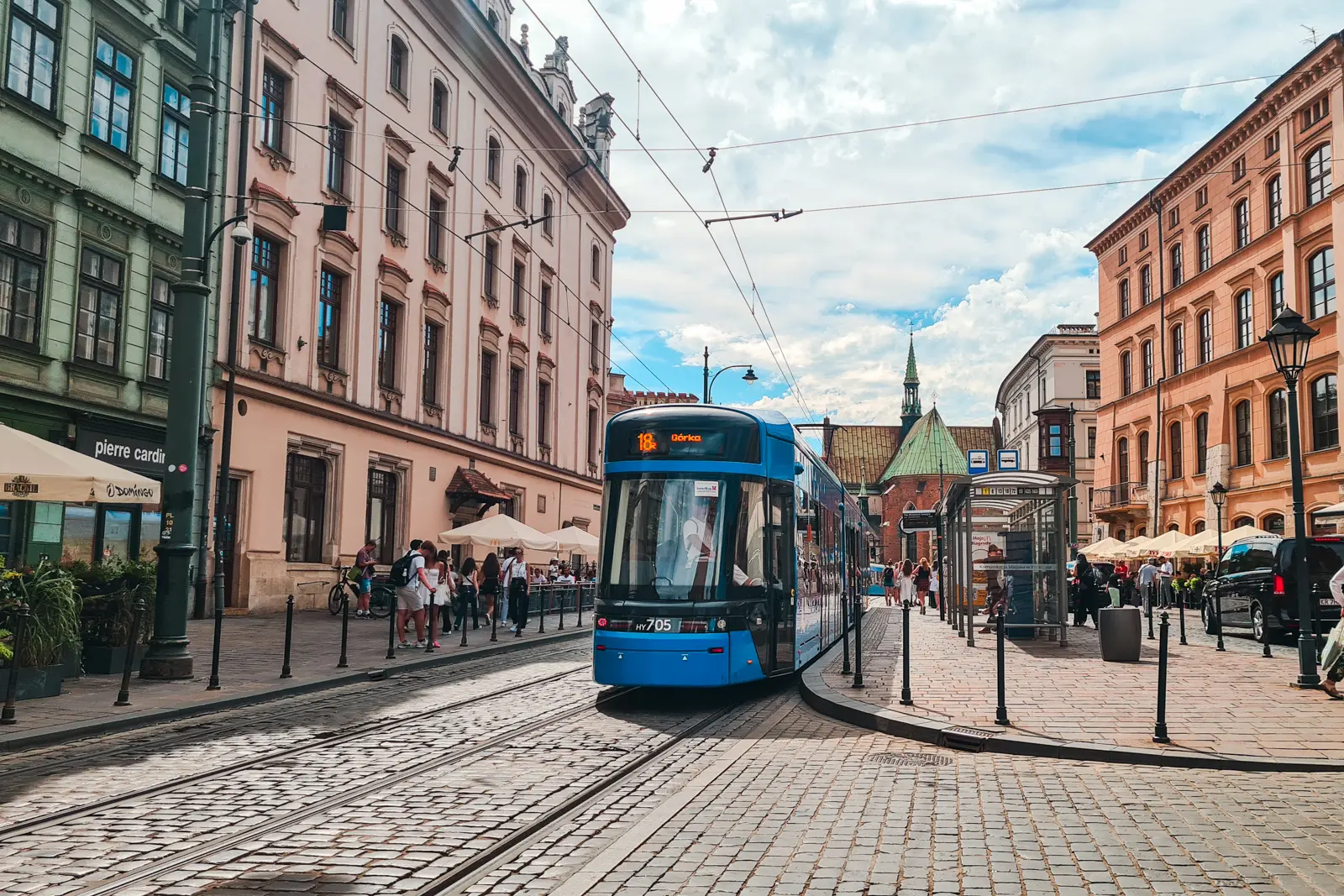 Blue tram on a cobbled street in Krakow's Old Town with old apartment buildings on both sides, a 2 days weekend in Krakow.