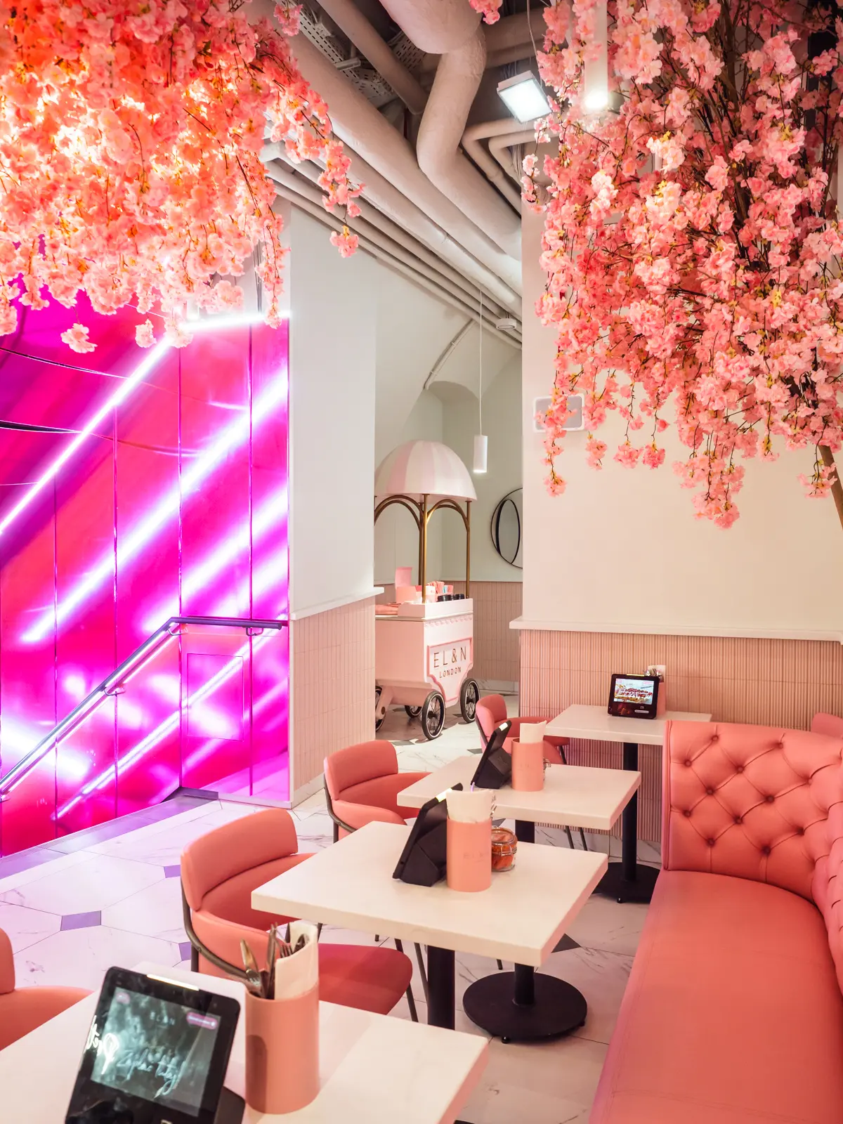 Pink leather sofa and chairs around white temples with a pink wall in the background and pink cherry blossoms in the ceiling at EL&N on a weekend in Krakow.