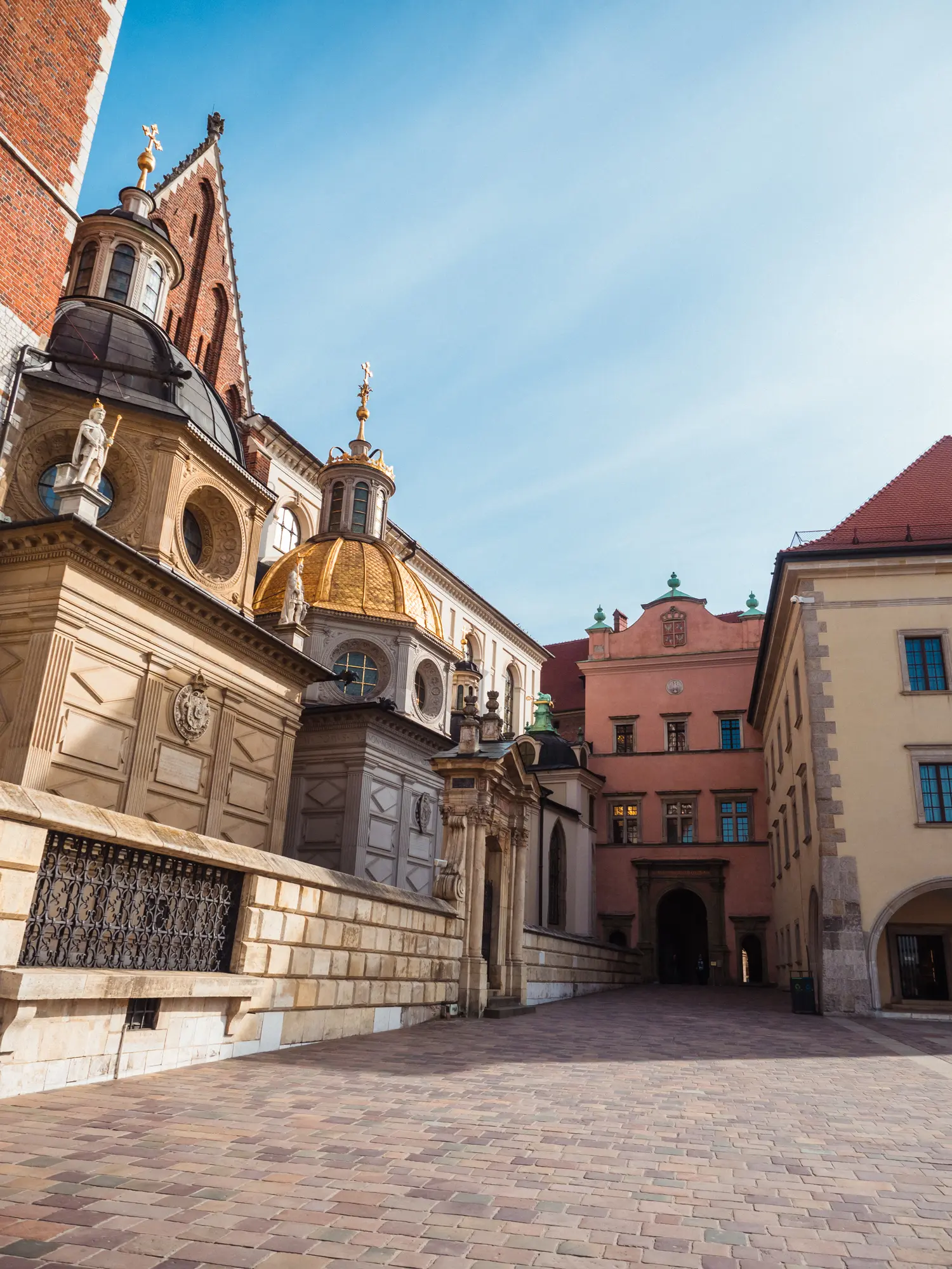 Two domes at Wawel Cathedral with many different architectural styles, Wawel Castle in the background on a sunny day, a must during your weekend in Krakow.