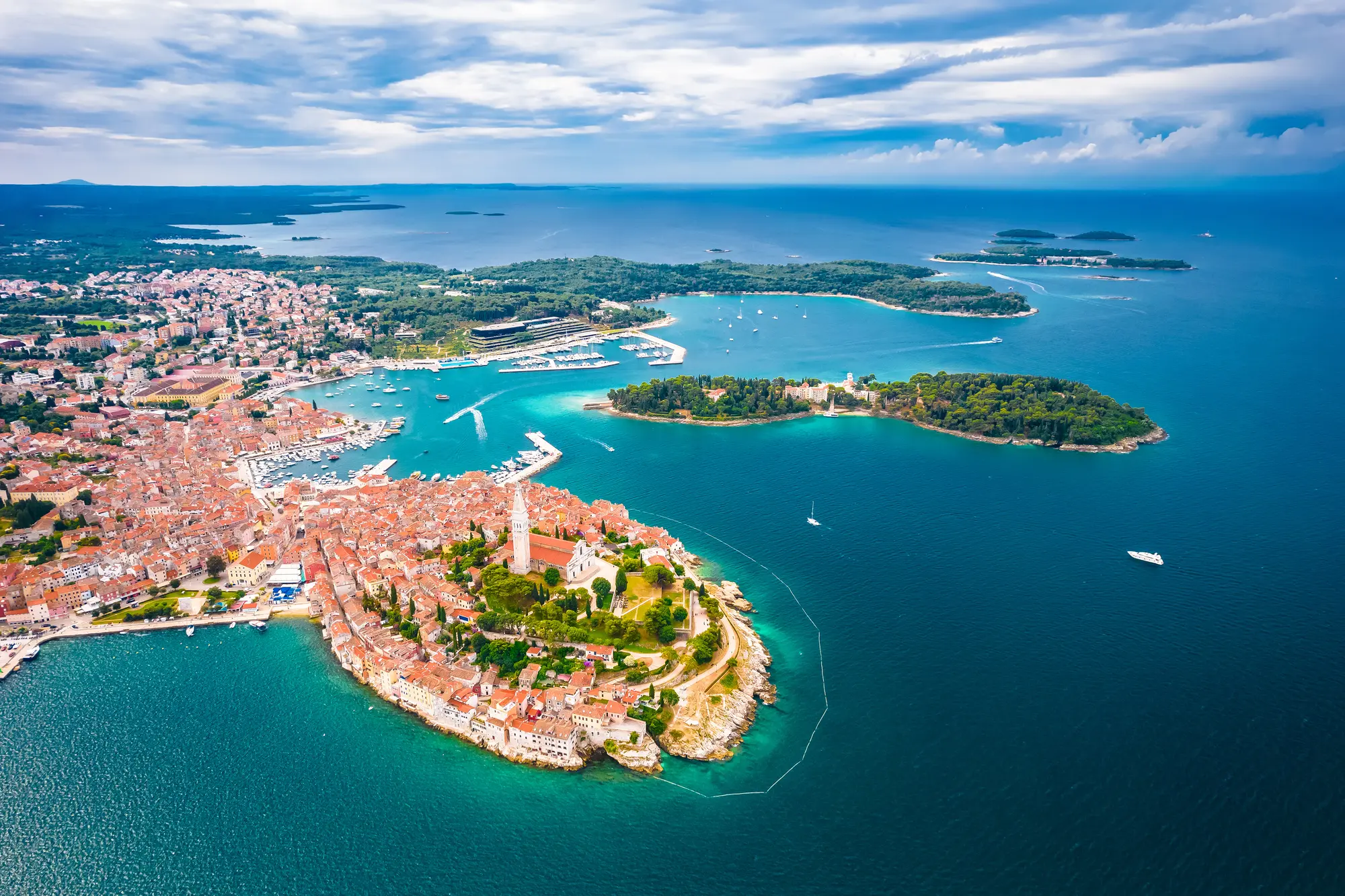 Aerial view of a Medieval town with red roofs on a peninsula in blue ocean with green islands in the background in Istria Croatia, one of the best summer destinations in Europe. 