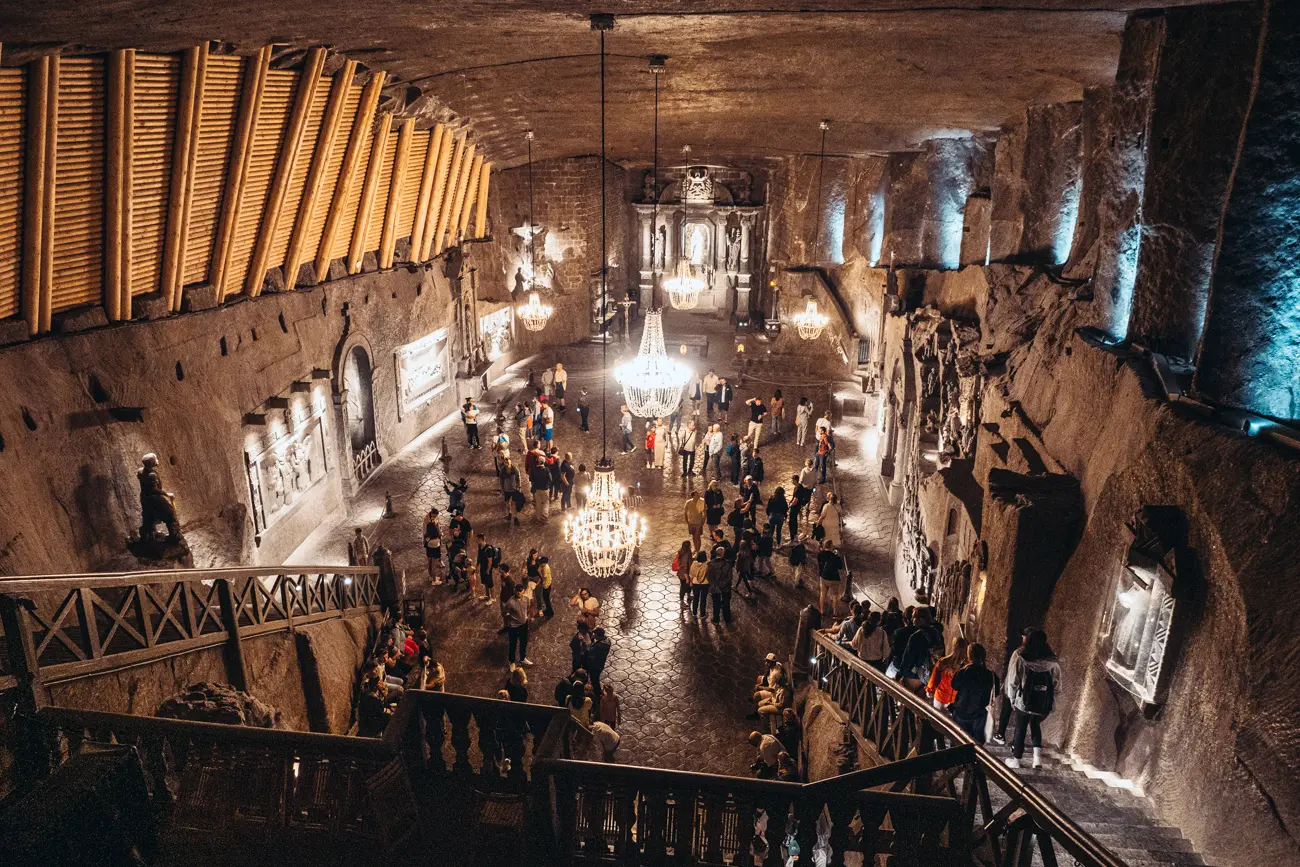 Looking from the top of the stairs at the large open cathedral room with three large chandeliers at Wieliczka Salt Mine on a weekend in Krakow.