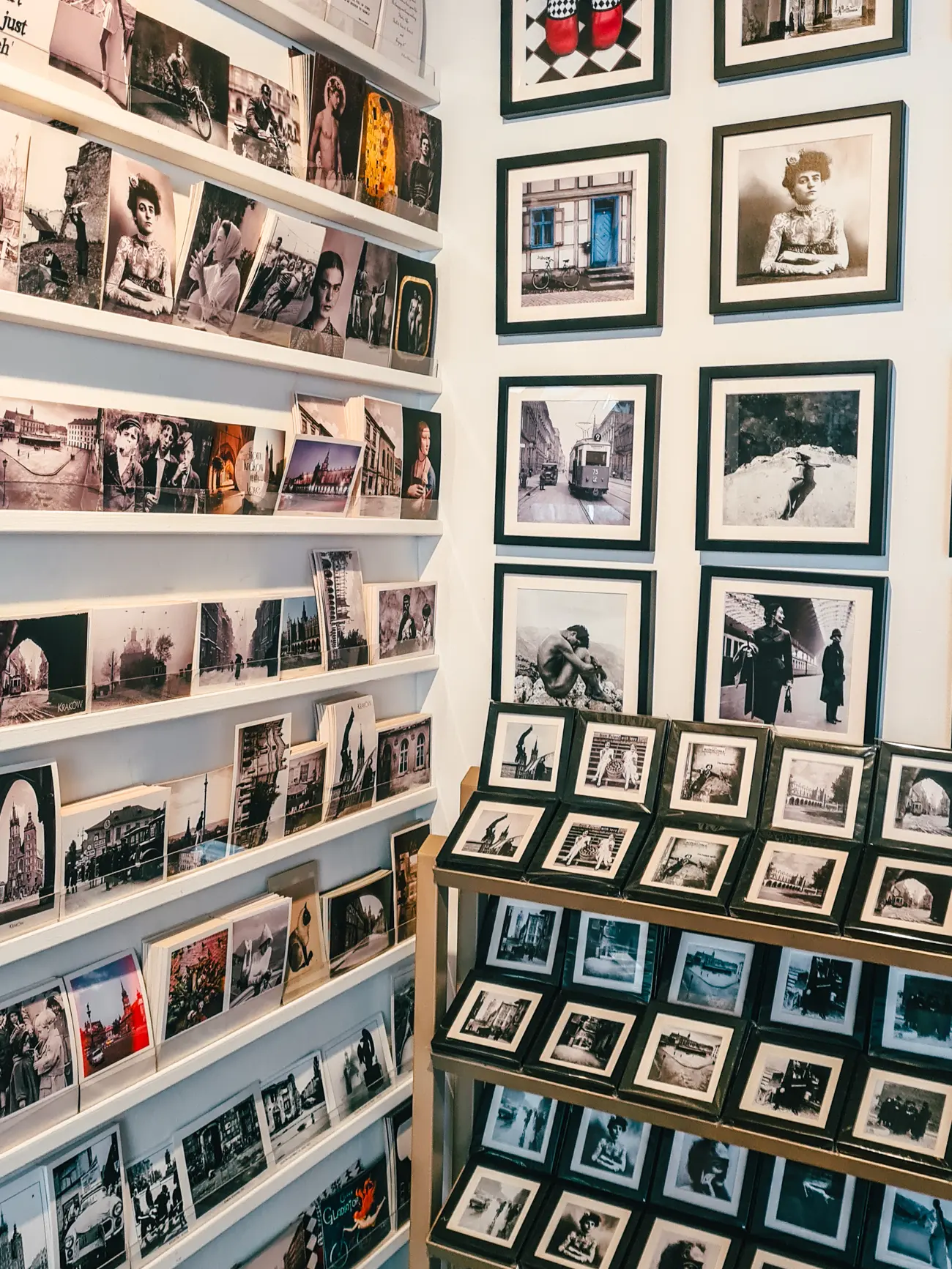 Old photos and postcards on a white wall in Galeria LueLue, one of the best boutiques and a hidden gem in Krakow.